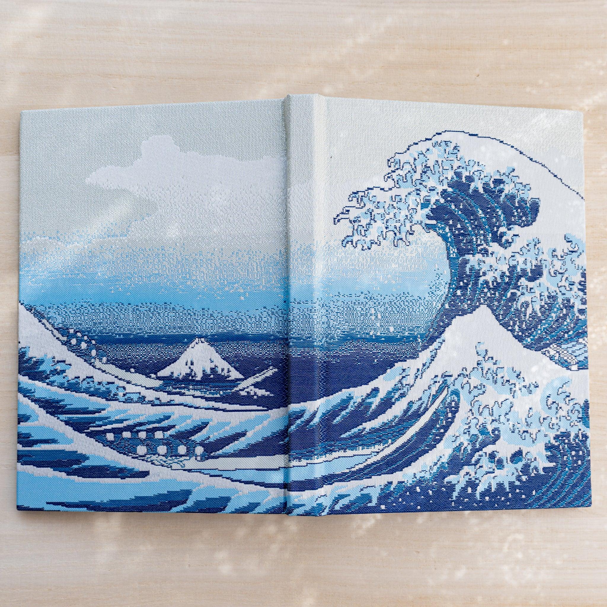 Notebook cover opened flat, woven textile spread of the Great Wave with small Mount Fuji and cresting blue waves