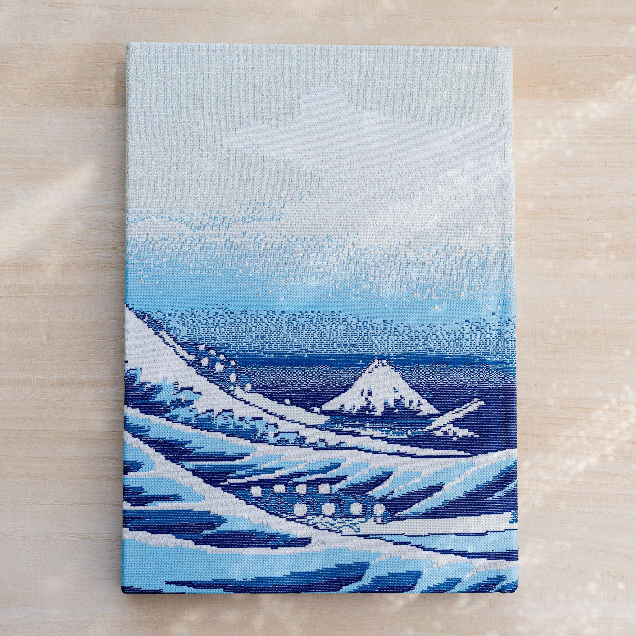 Notebook back cover in woven textile, blue waves with a small Mount Fuji in the distance under a pale sky