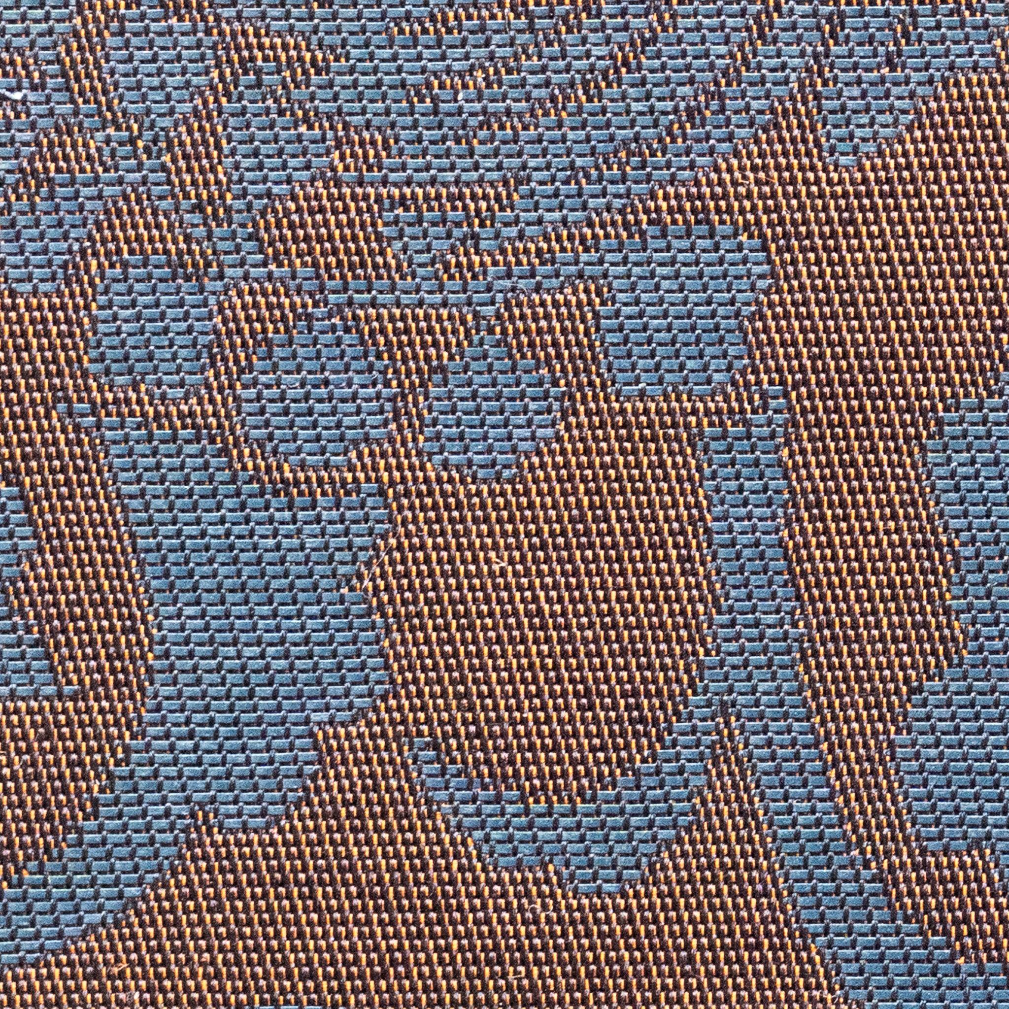 Extreme macro of Oni Kiri Nishijin silk showing individual woven thread structure with blue scroll motifs on copper-gold