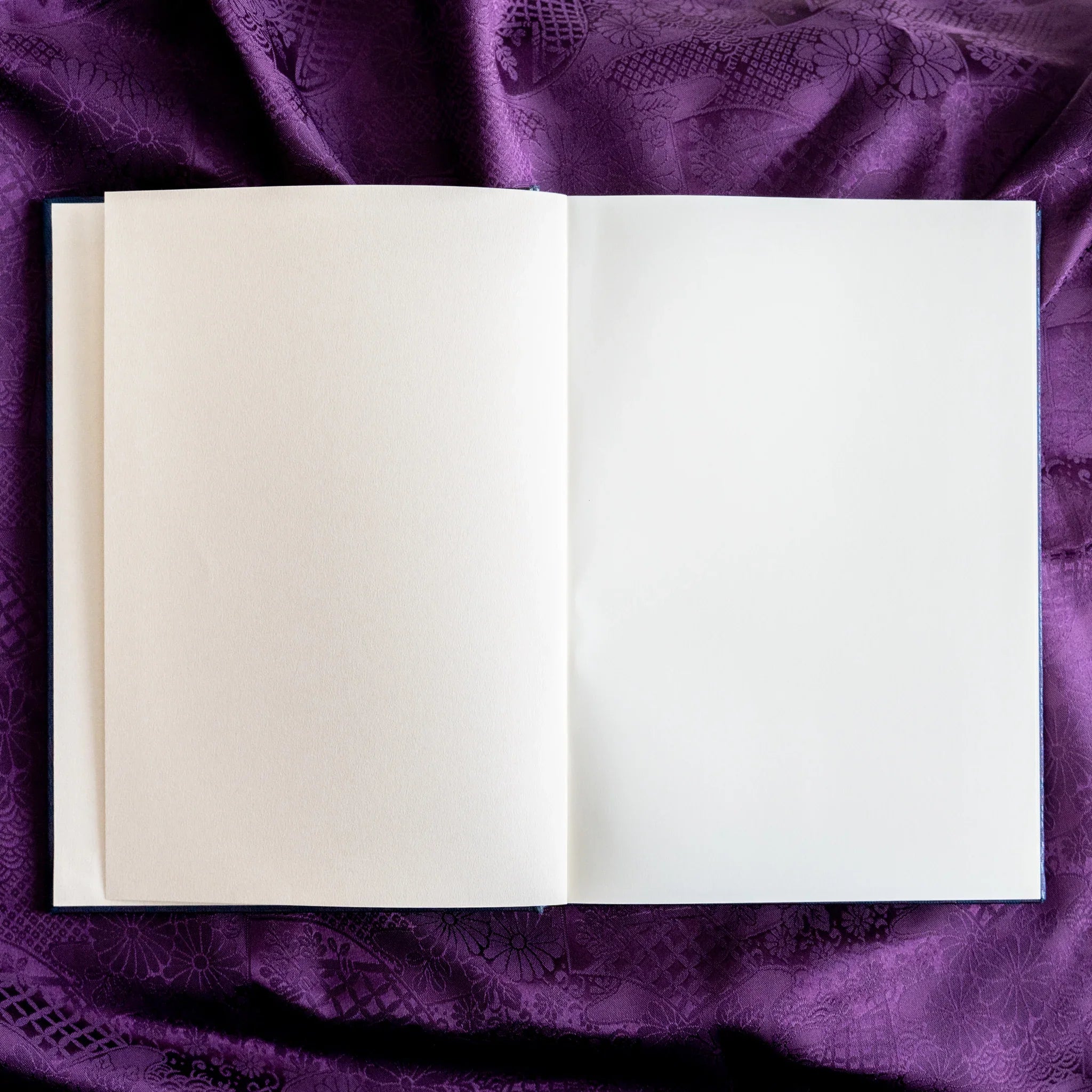 Oni Kiri Nishijin silk Homeicho notebook opened flat showing blank white pages and page stack edge on purple fabric