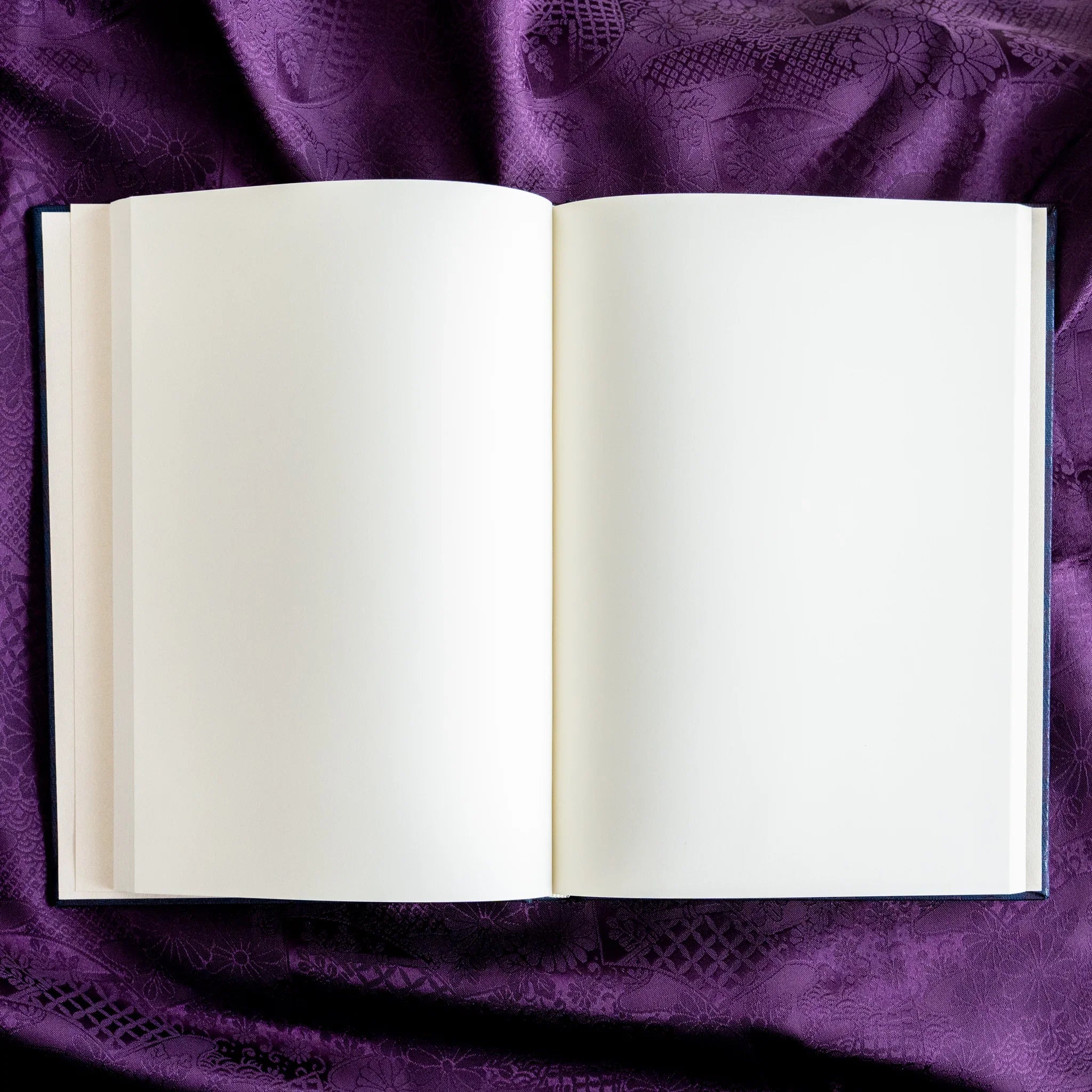 Oni Kiri Nishijin silk Homeicho notebook opened flat overhead with blank cream pages fully visible and dark blue cover edges