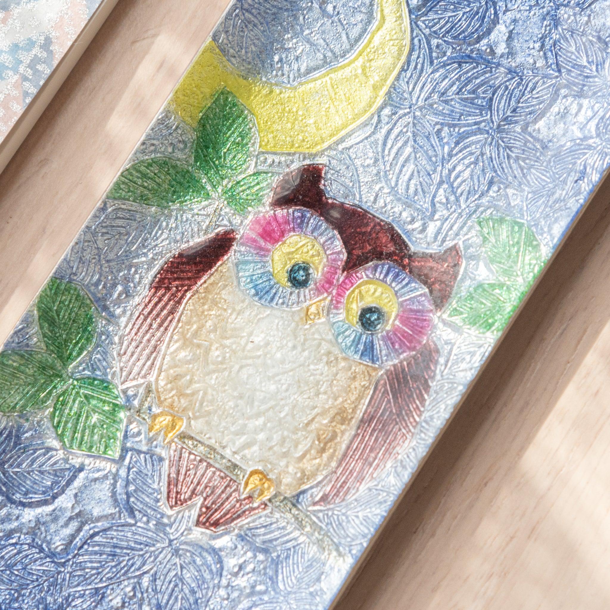 Close-up of a blue ceramic pen tray with a detailed owl design, featuring vibrant colors and a yellow crescent moon, highlighting its textured surface.