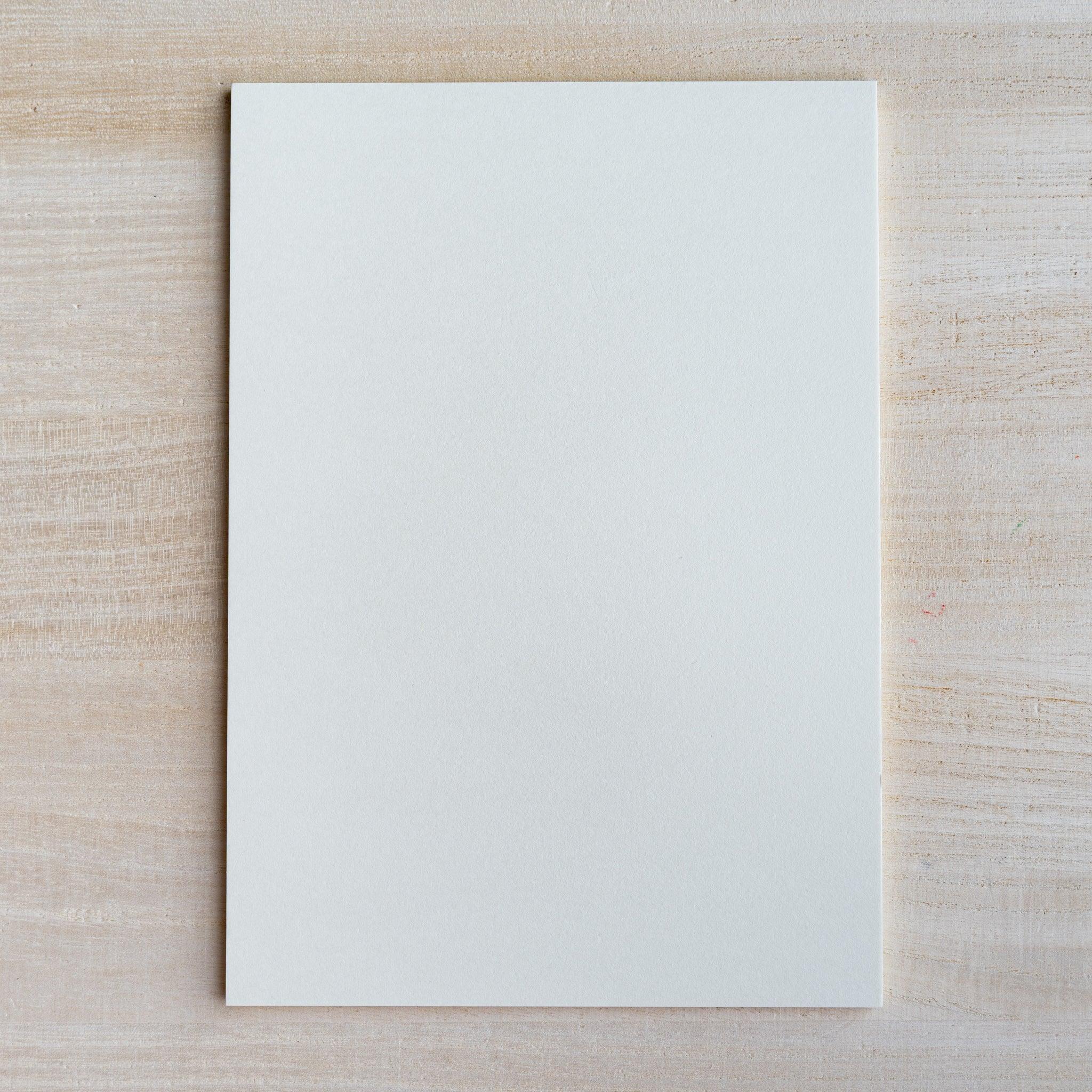 Single blank pale gray writing sheet laid flat on light wood surface