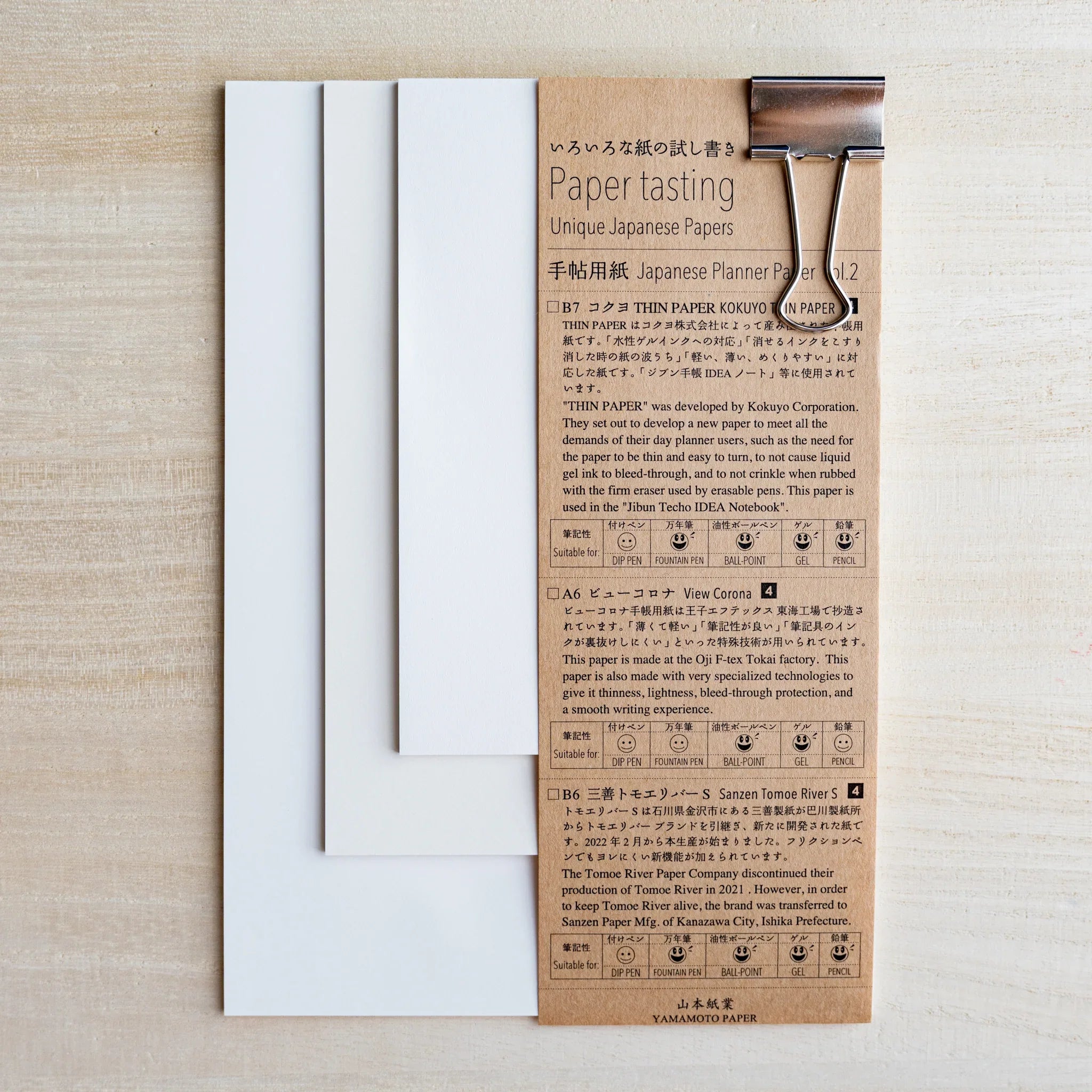 Paper tasting Japanese Planner Paper vol.2 set, white sample sheets fanned beside kraft cover with binder clip on wood