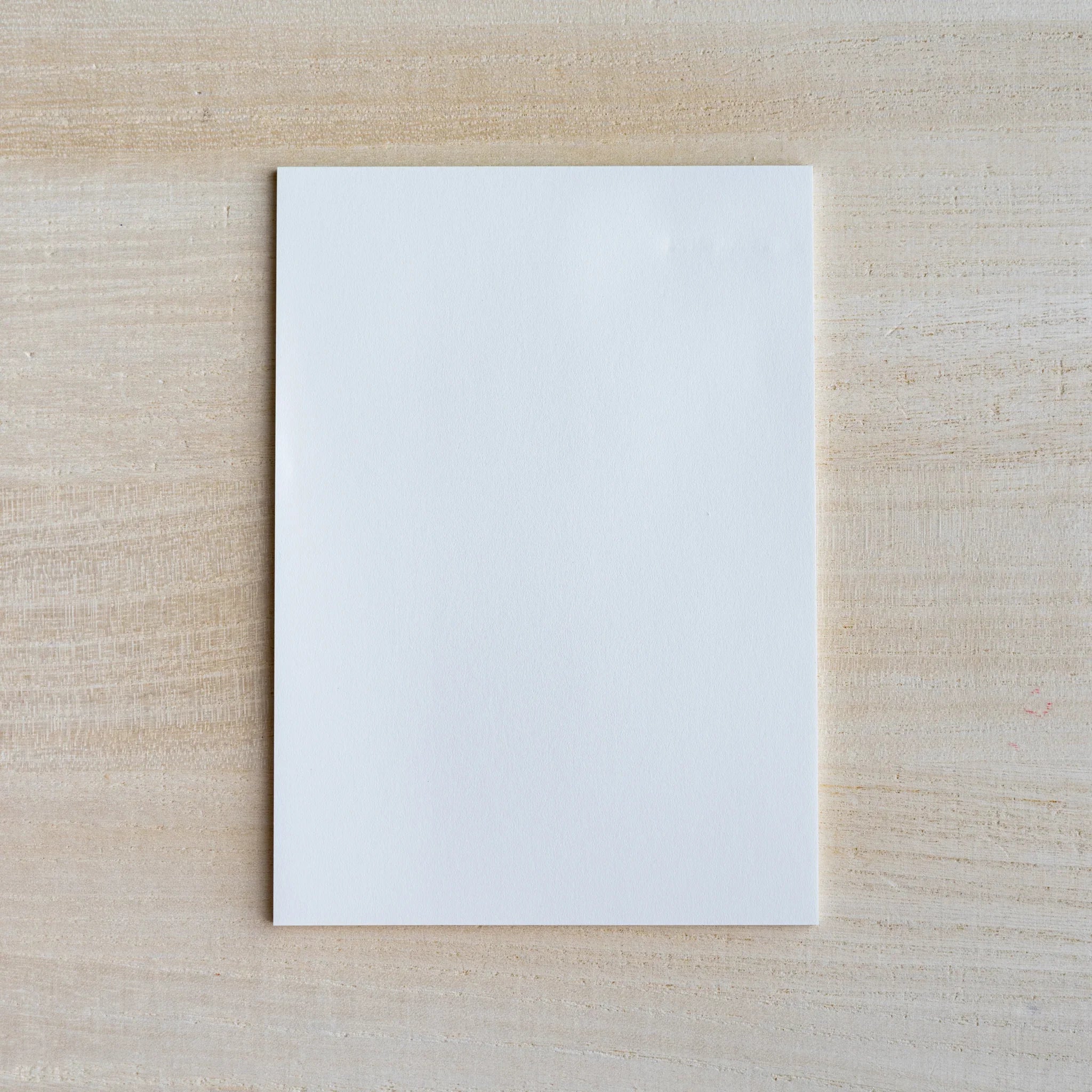 Single blank white sheet of Japanese writing paper on light wood surface