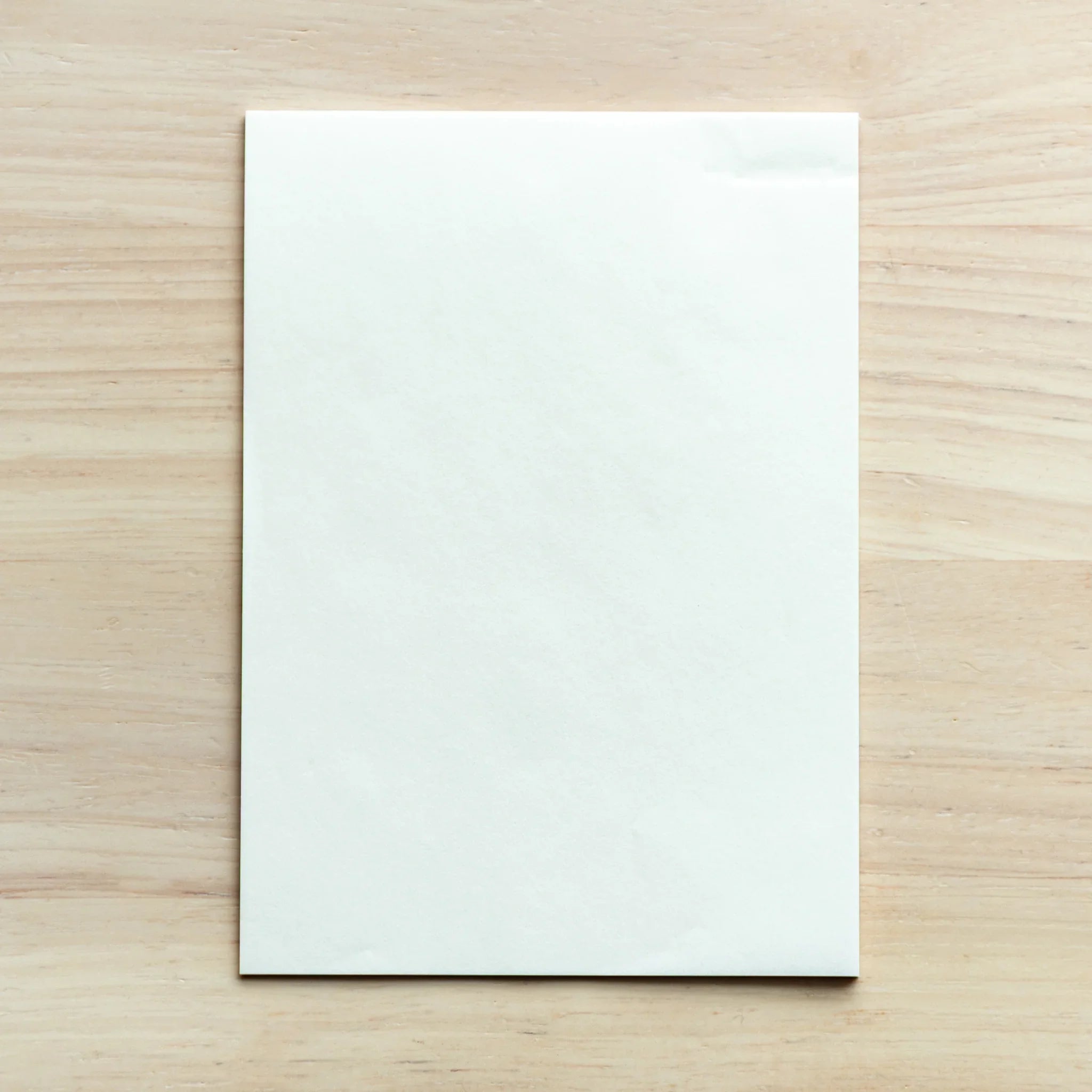 White onionskin writing pad from the Paper Tasting Set vol.2, pen-friendly and displayed on a wooden desk.