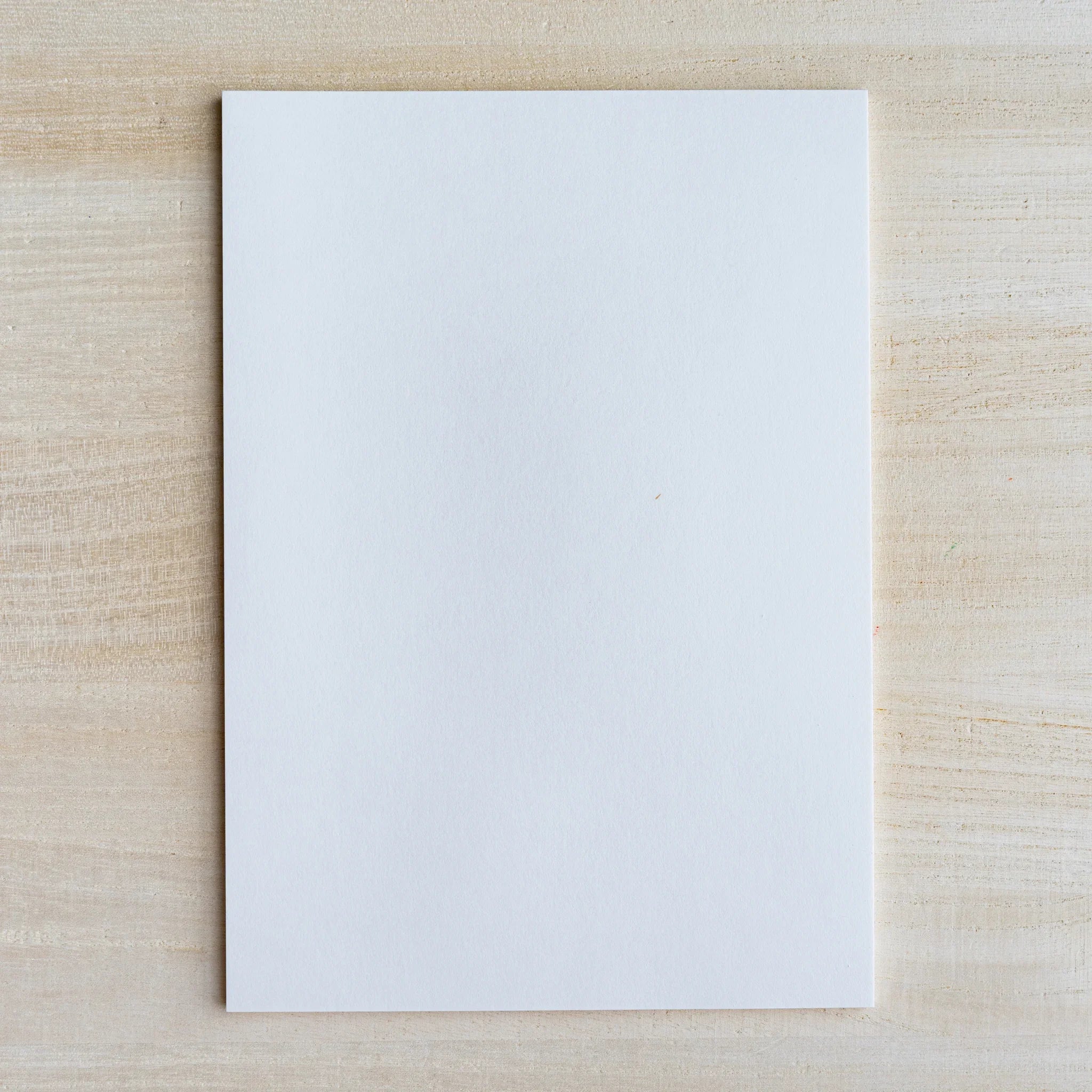 Blank white writing sheet laid flat on light wood surface
