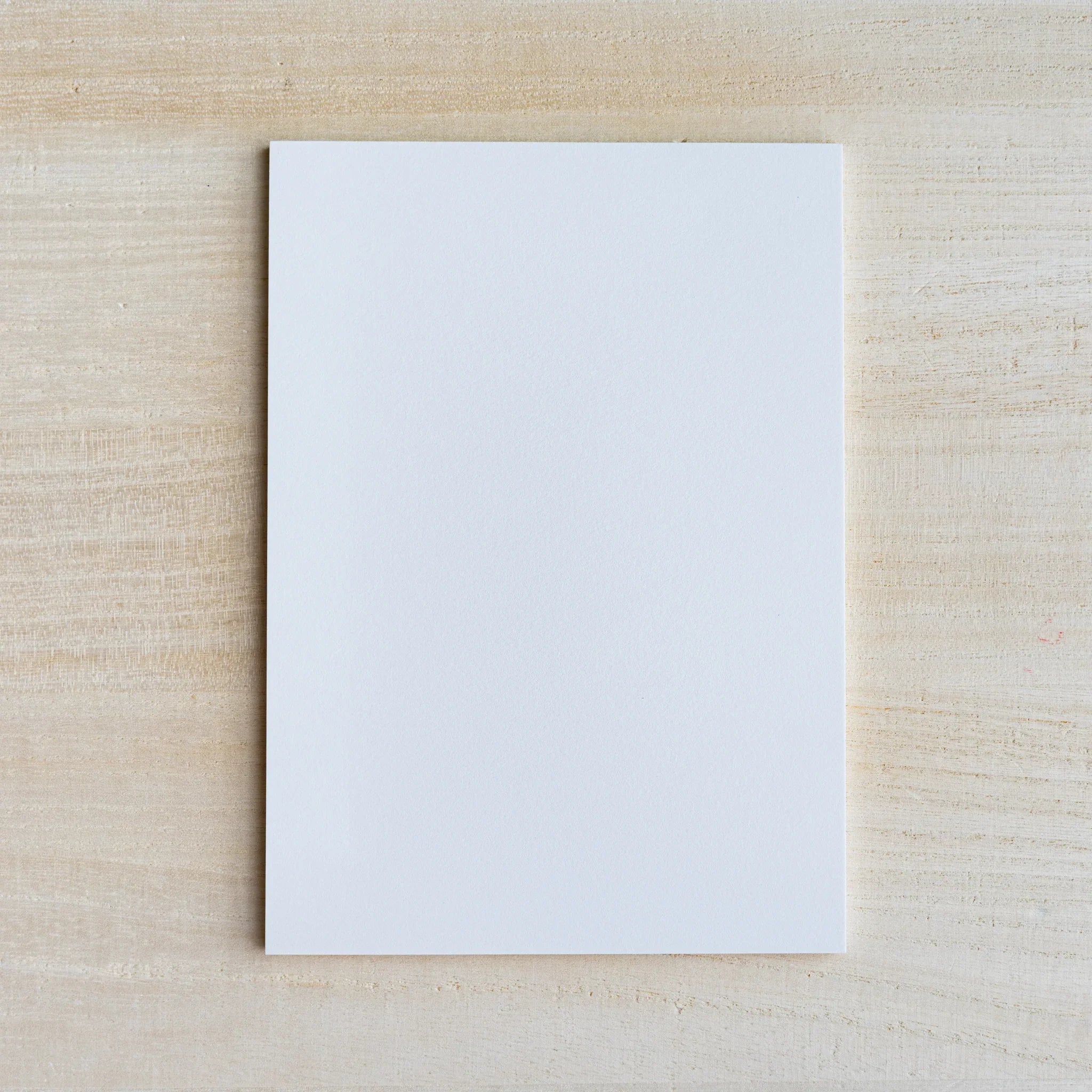 Single blank white writing sheet from the Silky pad on light wood