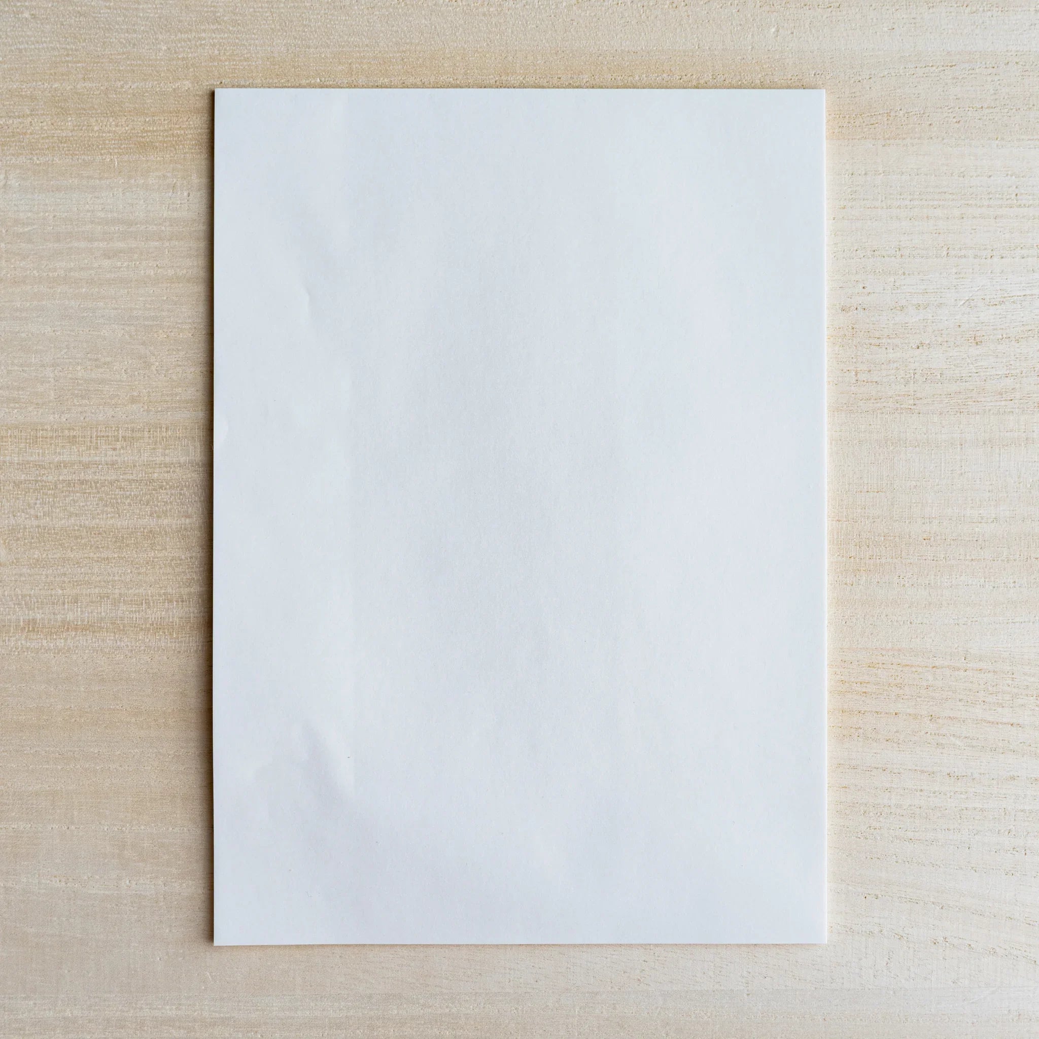 Single translucent semi-transparent writing sheet on light wood surface