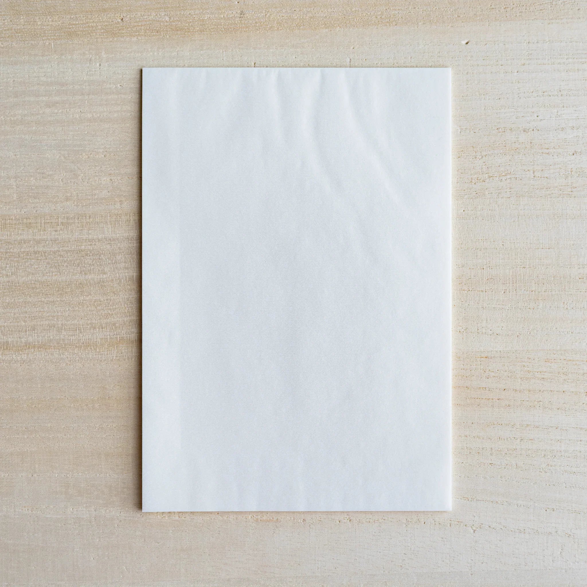 Single semi-transparent translucent sheet laid flat on light wood surface