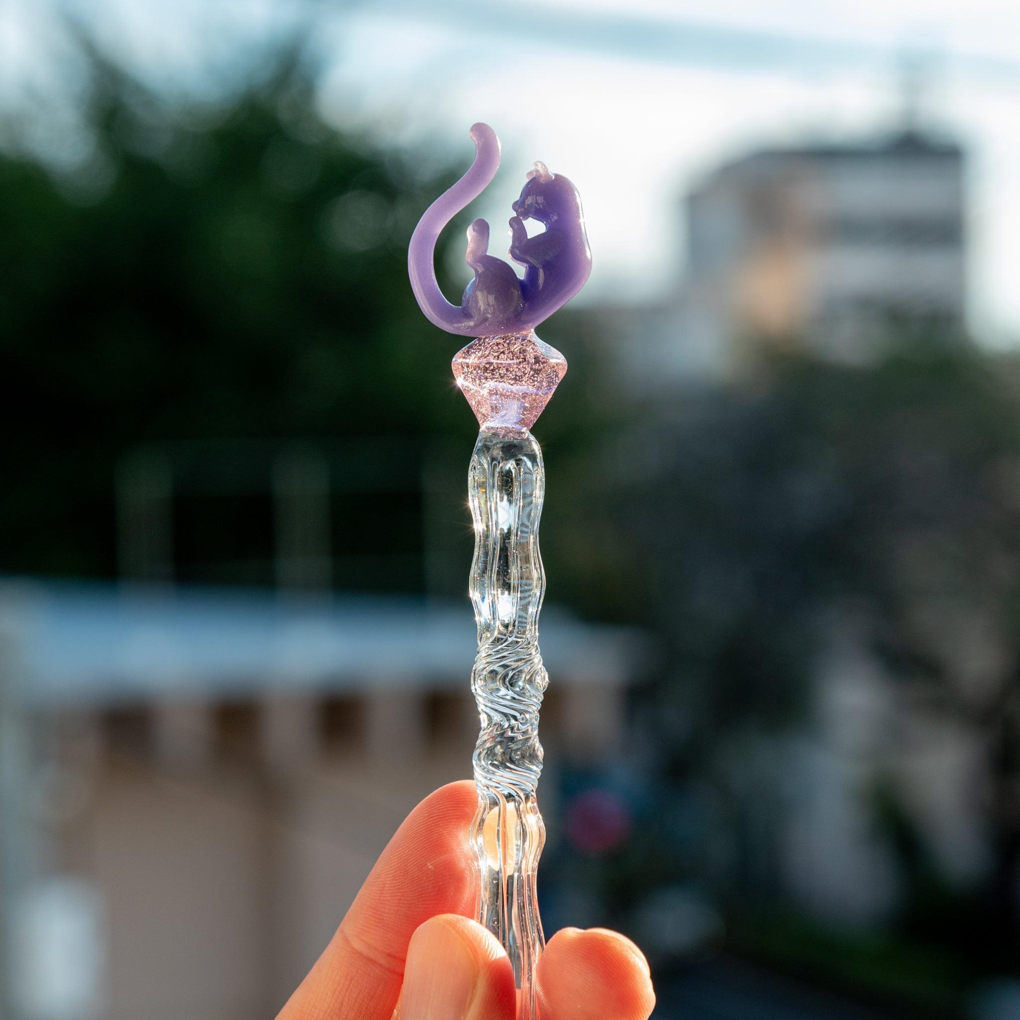 Handheld glass pen with a blue shaft, purple cat topper, and pink charm. Perfect for Japanese stationery lovers.