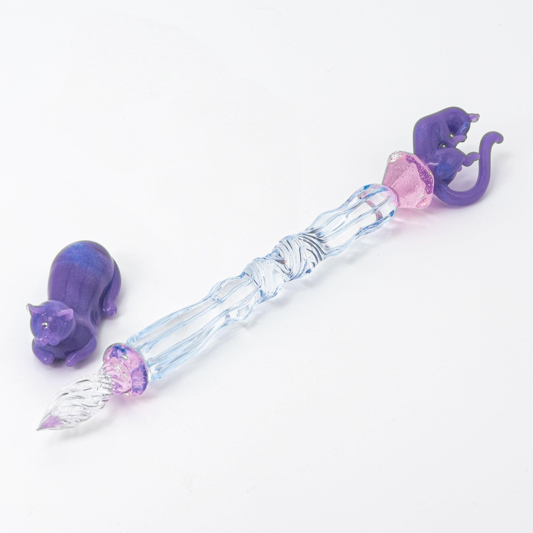 Glass pen with a blue shaft, purple cat topper, and pink charm. Includes matching purple pen rest. Perfect for Japanese stationery lovers.