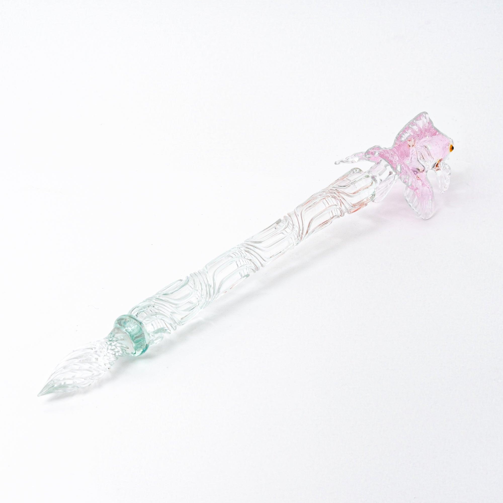 The pink goldfish glass pen photographed on a white background, displaying the clear glass body and the intricately sculpted goldfish in pink glass at the top.