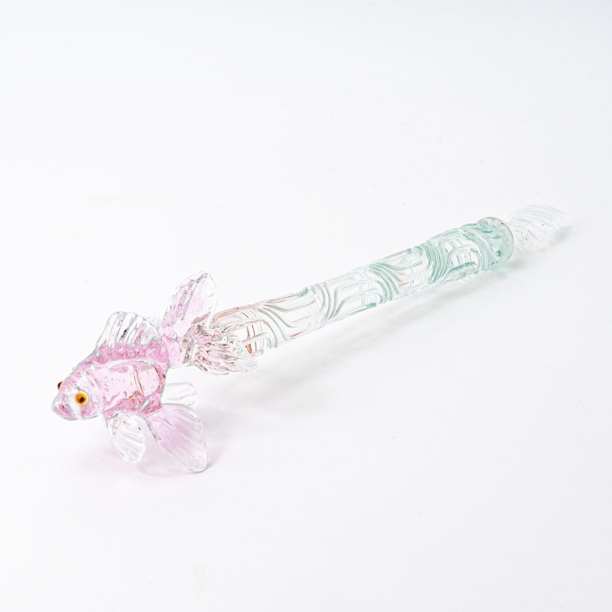 The pink goldfish glass pen photographed on a white background, displaying the clear glass body and the intricately sculpted goldfish in pink glass at the top.