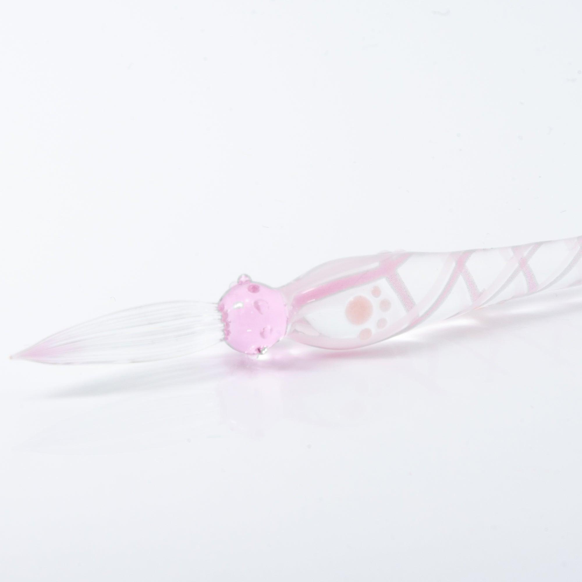 A delicate pink glass dip pen featuring a cat design at the top and a twisted, clear handle, creating a whimsical and elegant look.