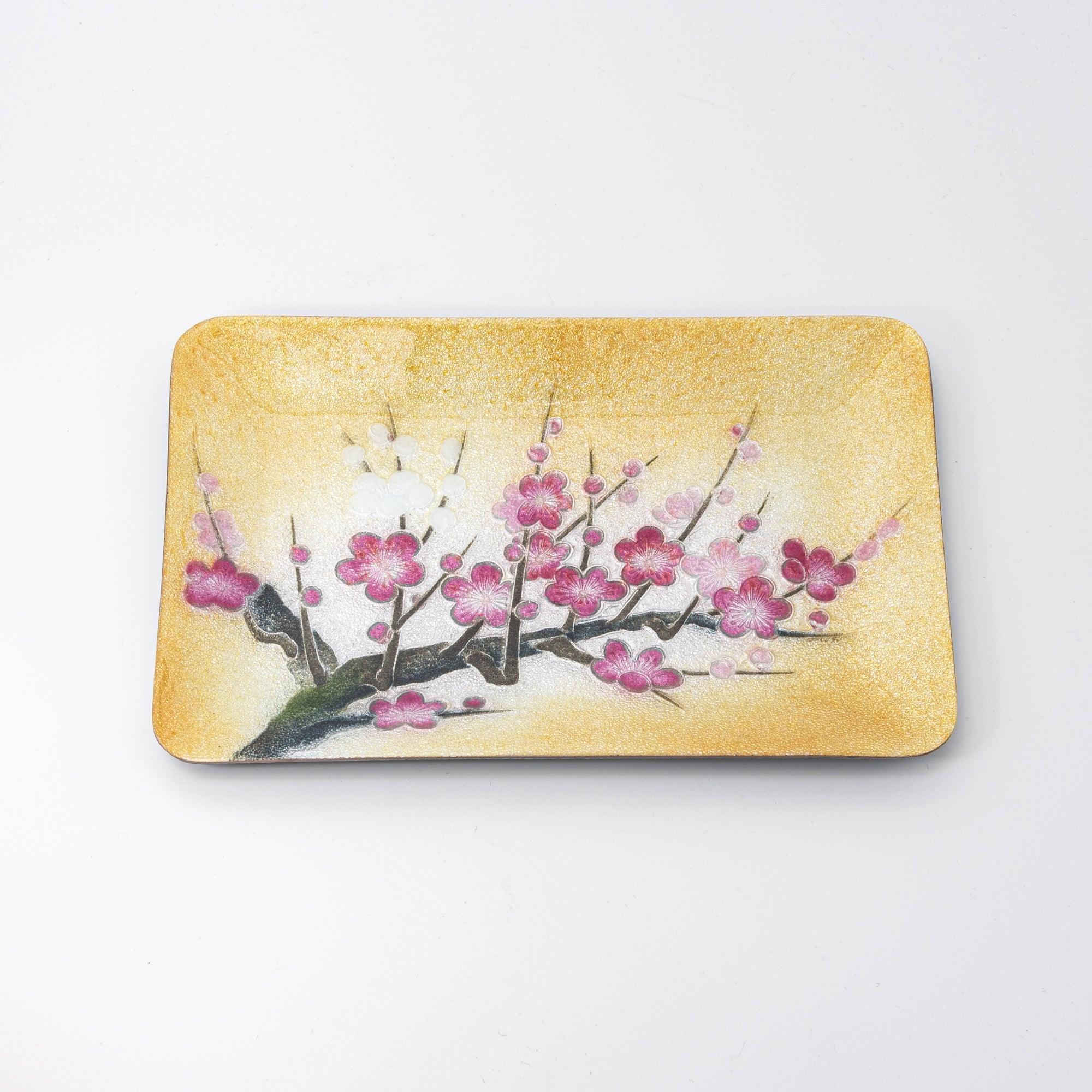 A flat view of a golden tray featuring pink and white plum blossoms, highlighting the intricate details of Japanese design.  