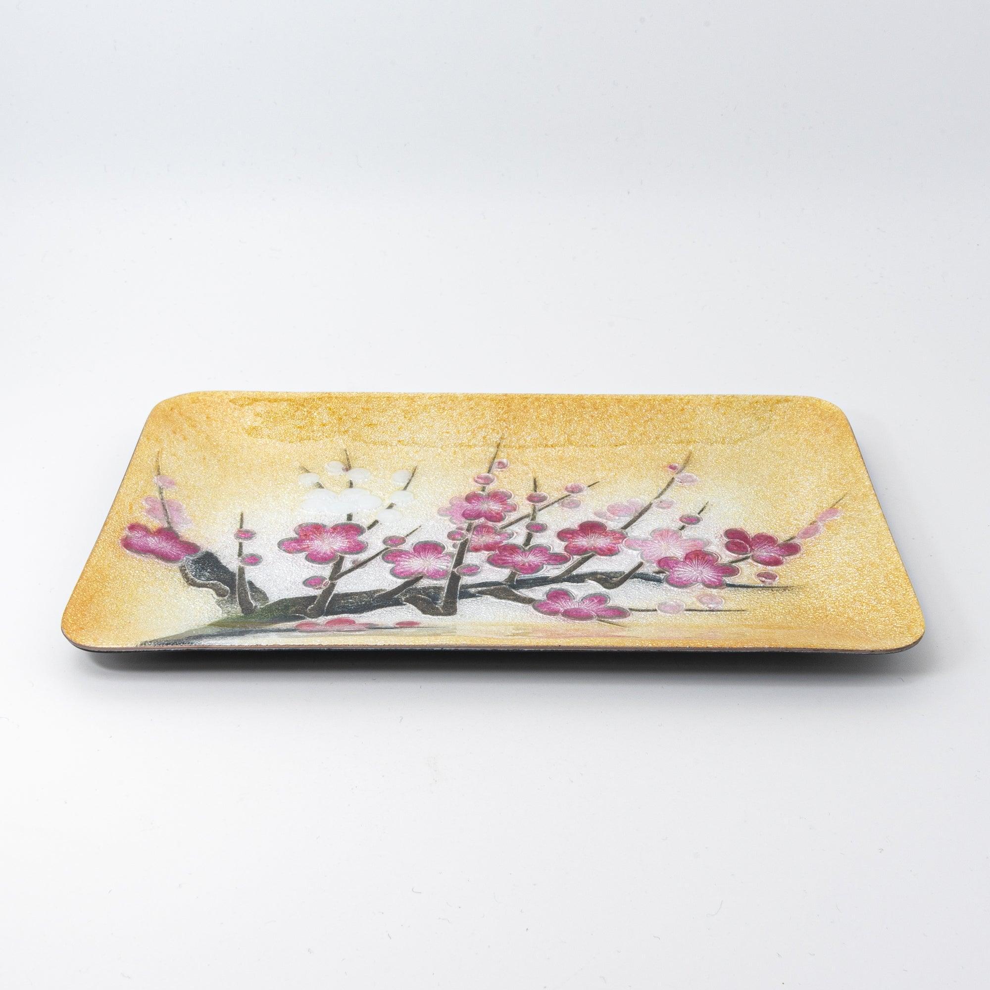 A side view of a golden tray adorned with vibrant plum blossom branches, emphasizing its textured surface and elegant motif.  