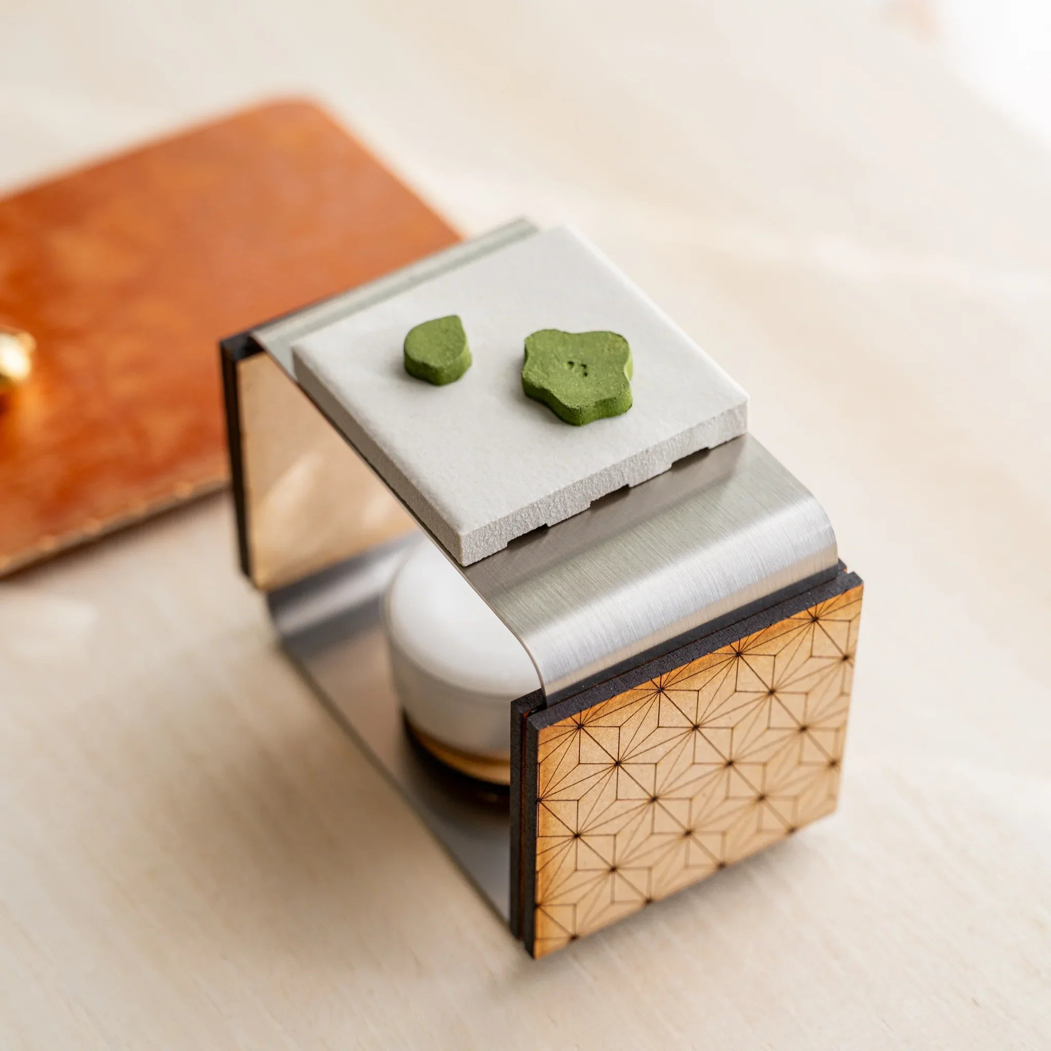 Foldable matcha incense tea warmer with asanoha wood and ceramic plate holding two plum-shape pressed matcha incense pieces