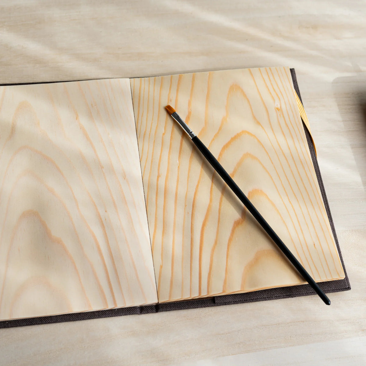 Red Pine Wooden Page Sketchbook Brown open to two wood sheet pages, paintbrush resting on the right page