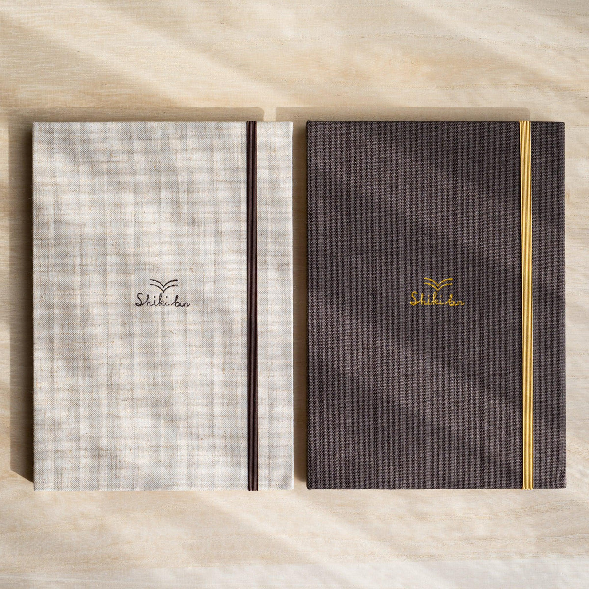 Red Pine Wooden Page Sketchbook Natural and Brown side by side, linen covers with dark brown and yellow elastic bands