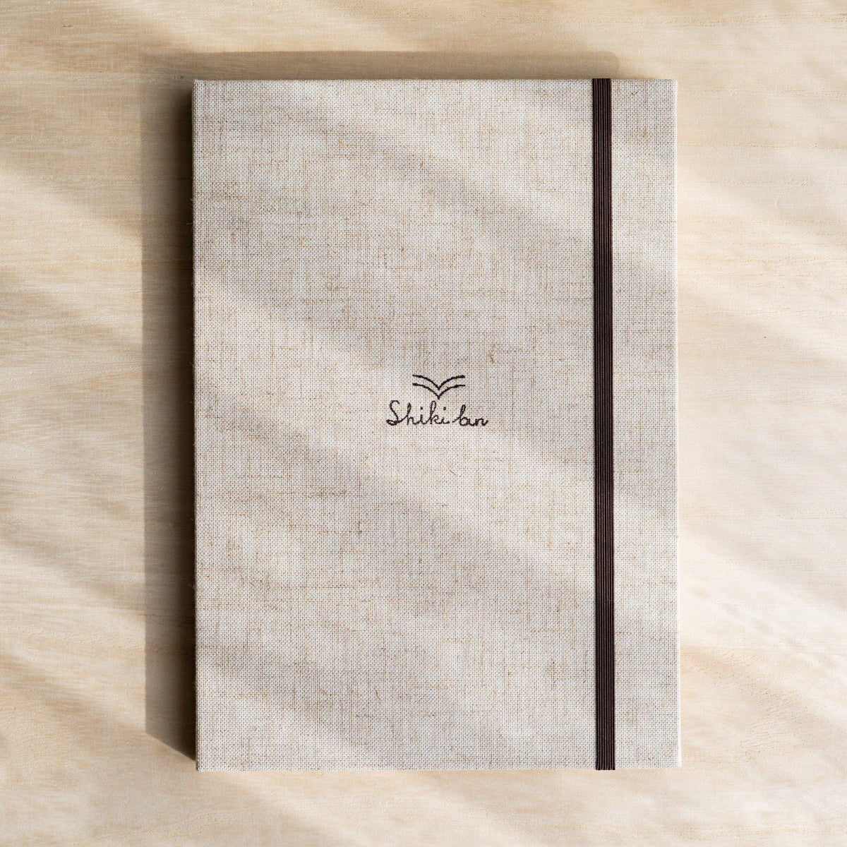 Red Pine Wooden Page Sketchbook Natural, undyed linen cover with Shiki bun logo and dark brown elastic band