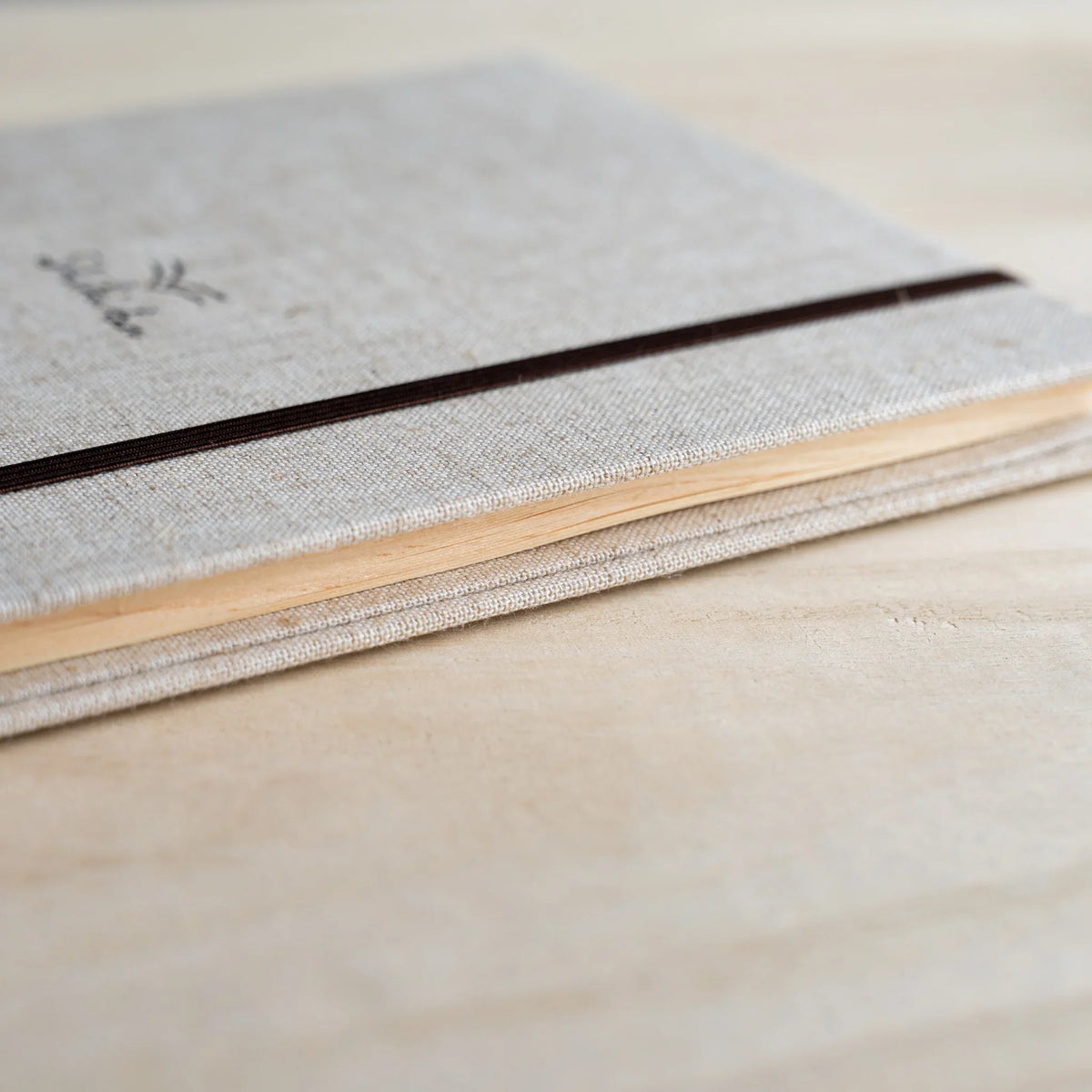 Side view of the Red Pine Wooden Page Sketchbook Natural closed, wood page edges between linen covers