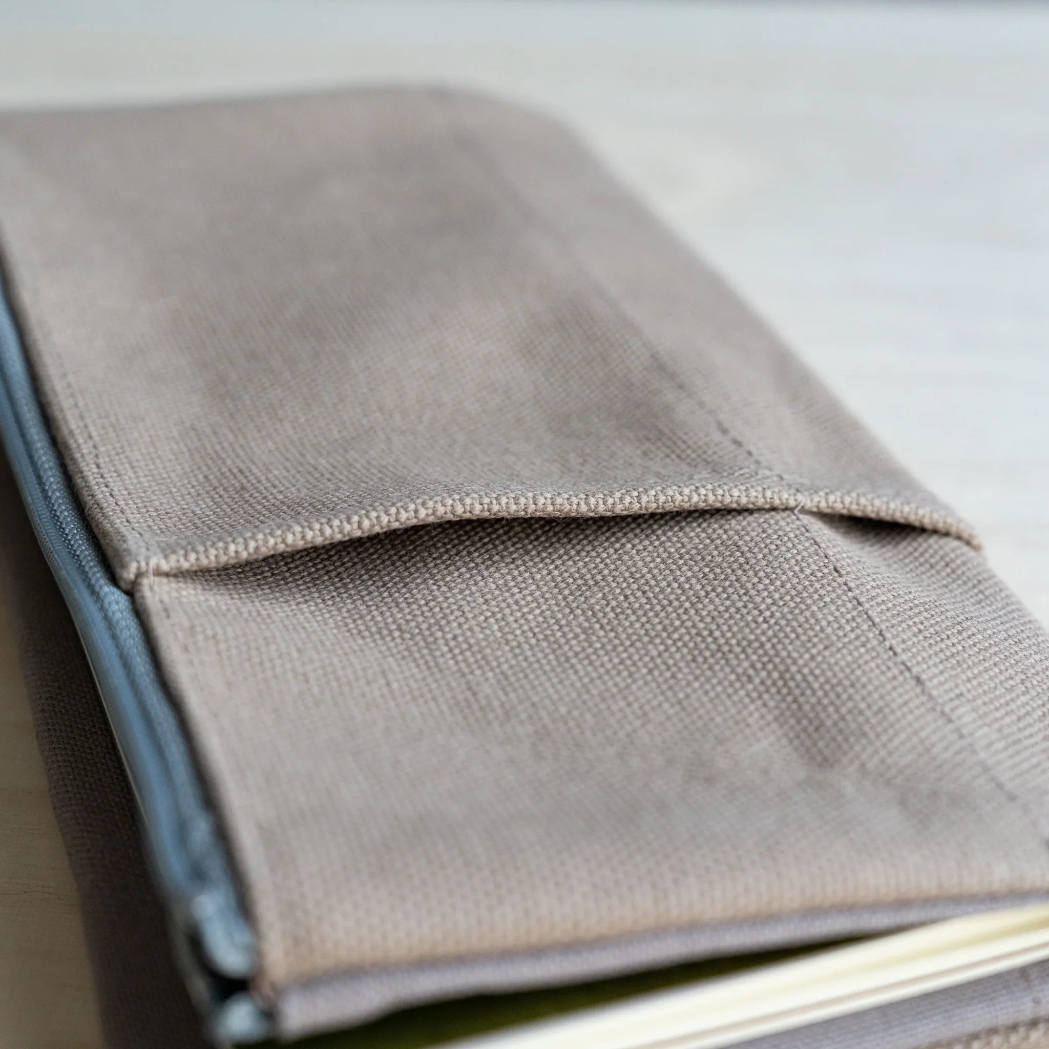 Close-up of the front pocket seam and the pale blue side zip on the RO-BIKI clay beige canvas cover