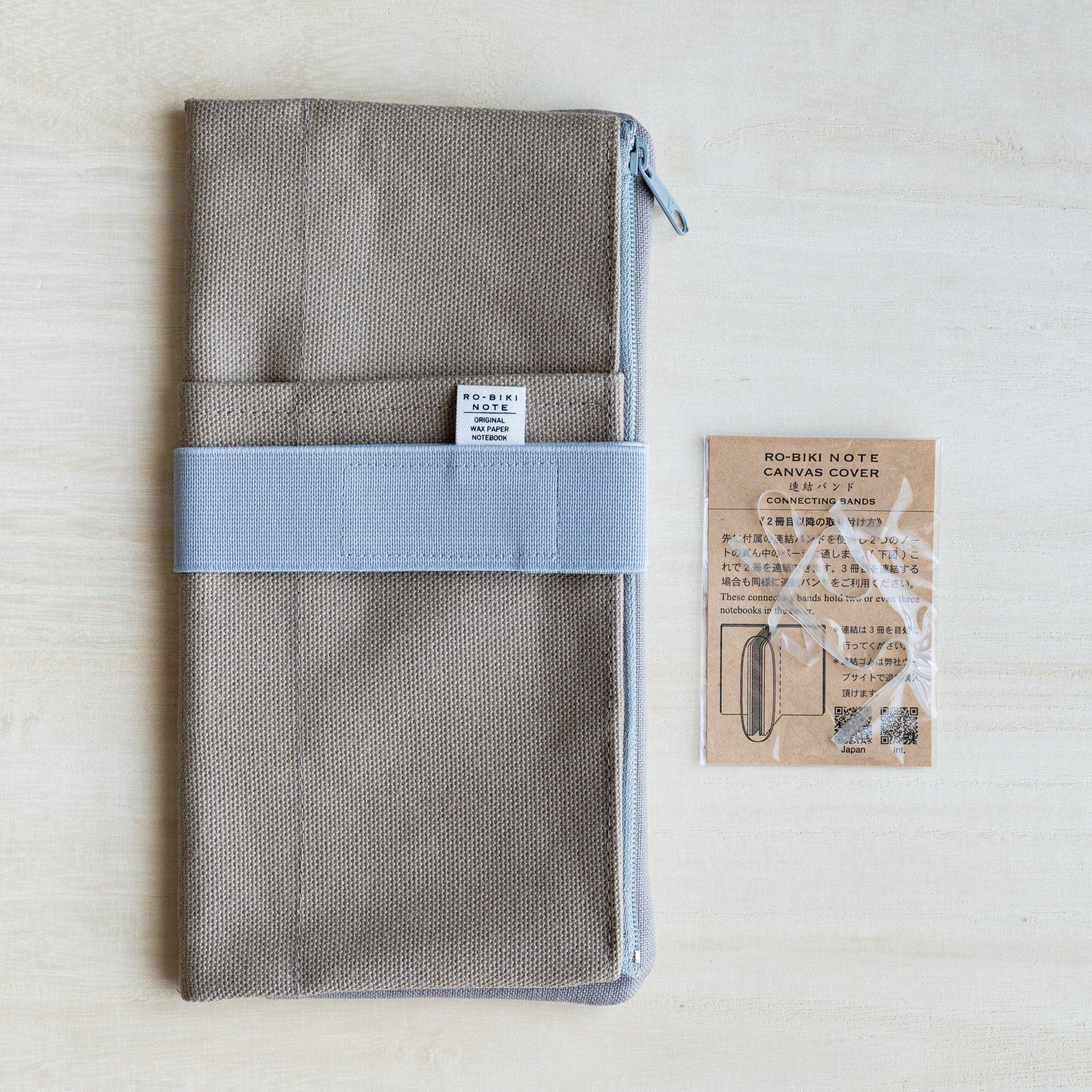 RO-BIKI clay beige canvas cover folded with a pale blue elastic band and the kraft connecting bands card