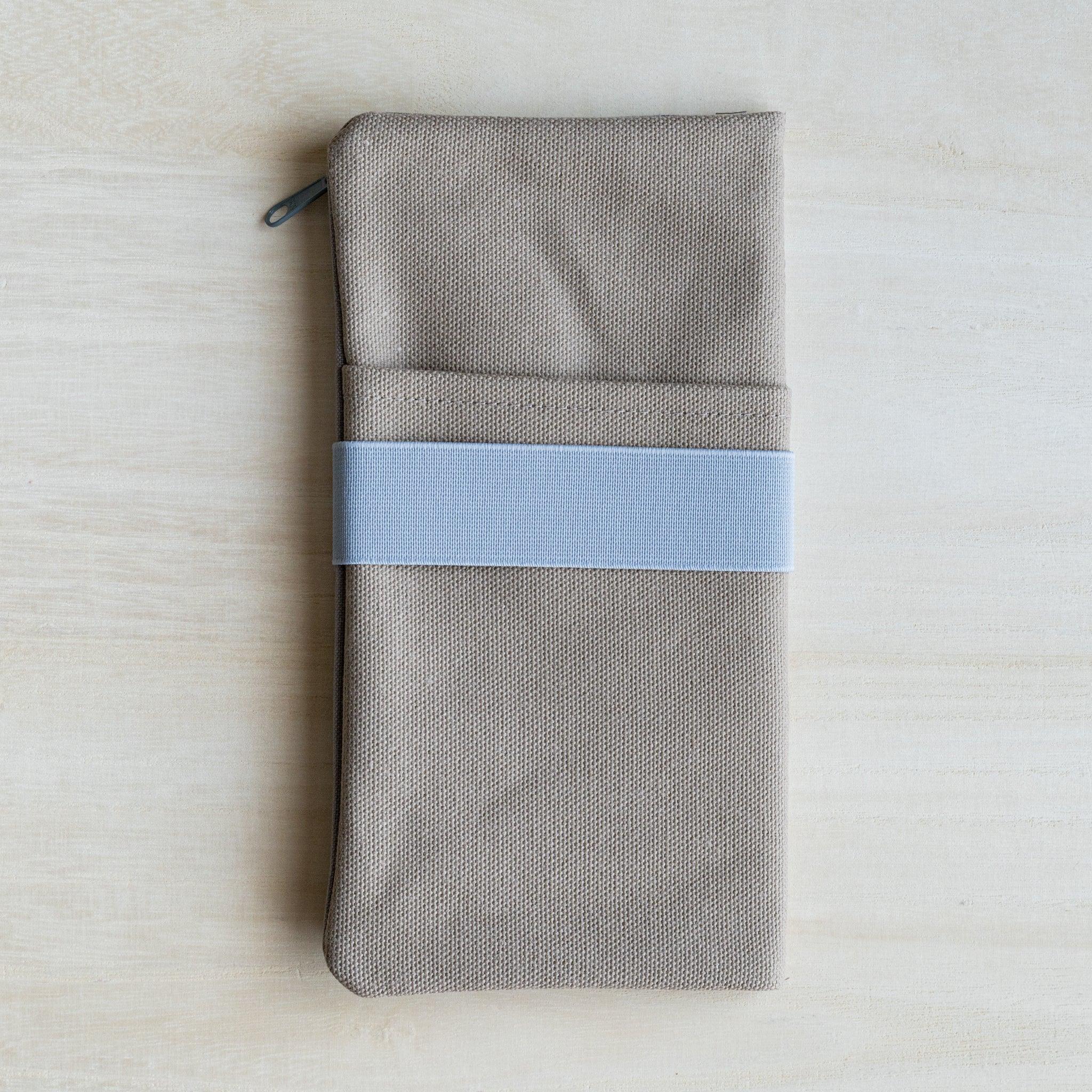 RO-BIKI clay beige canvas cover closed, showing front slip pockets, a pale blue elastic band and a side zip