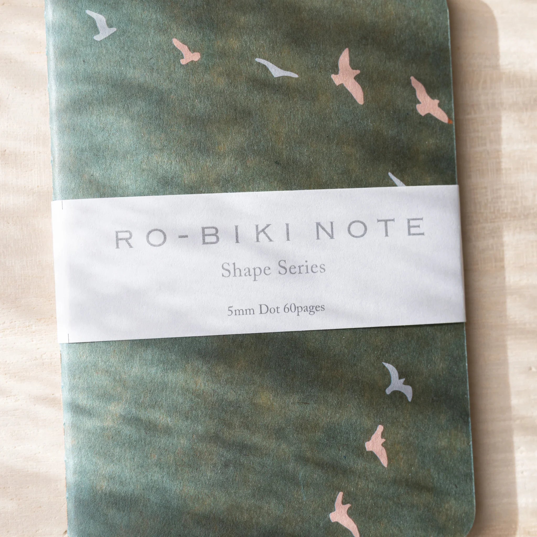 RO-BIKI NOTE close-up with sage green waxed cover showing flying bird design, Japanese craft visible