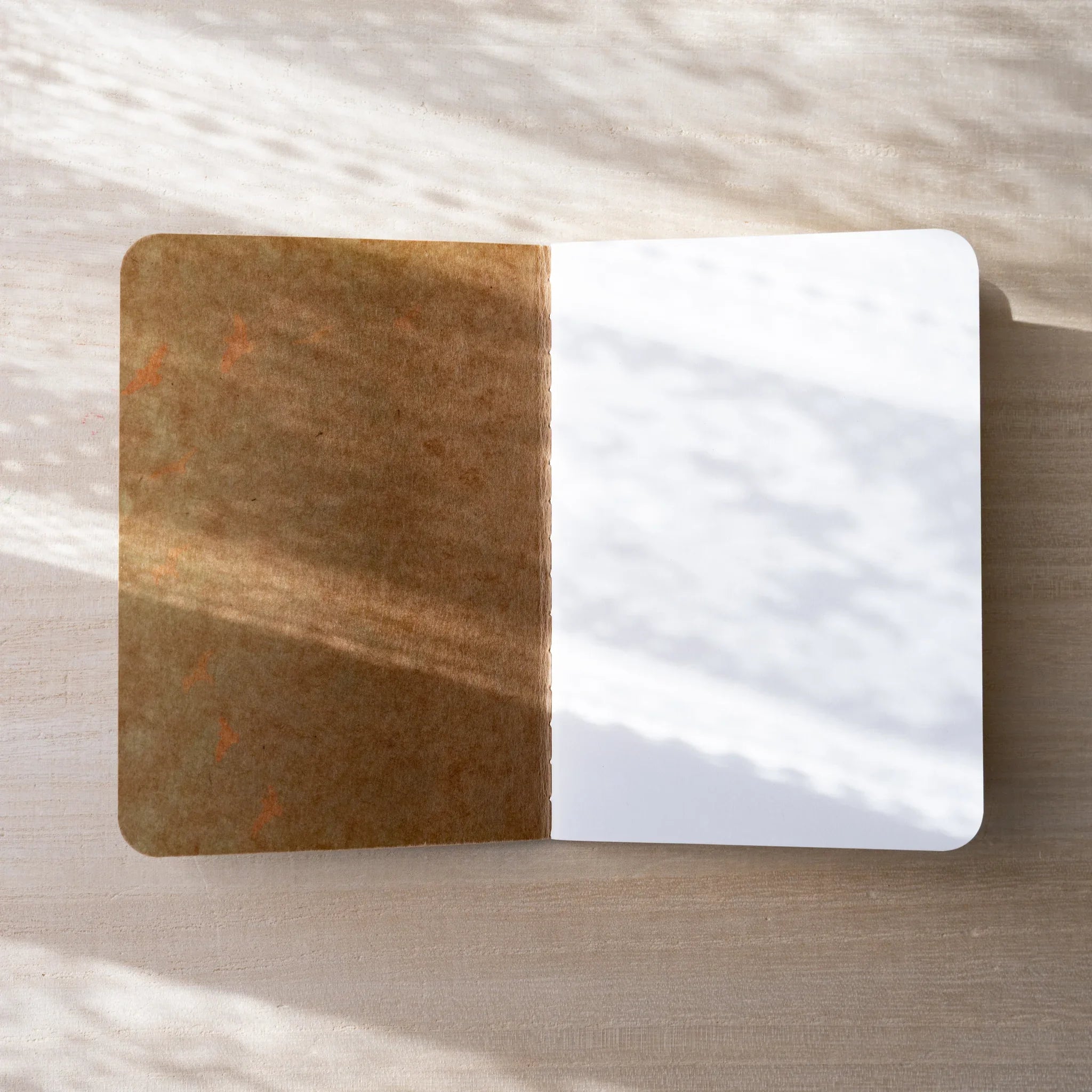 RO-BIKI NOTE Japanese notebook open flat, brown waxed kraft inner cover on left, blank white page on right, rounded corners