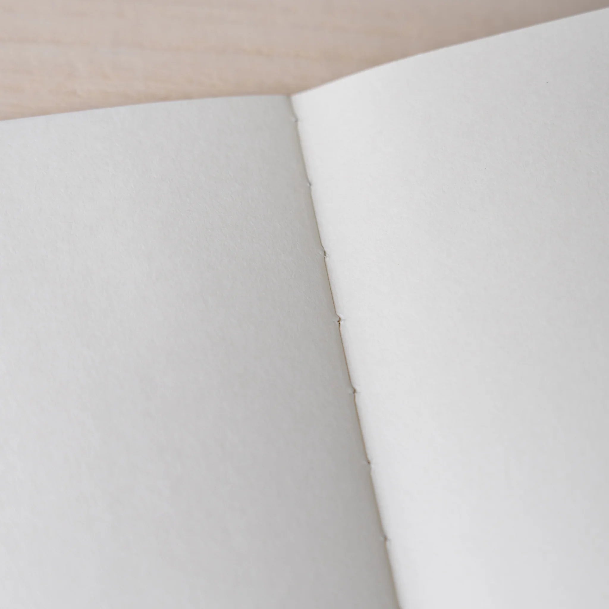 Close-up of RO-BIKI NOTE Ginnezu gray notebook spine binding with thread stitching and cream Solist paper texture