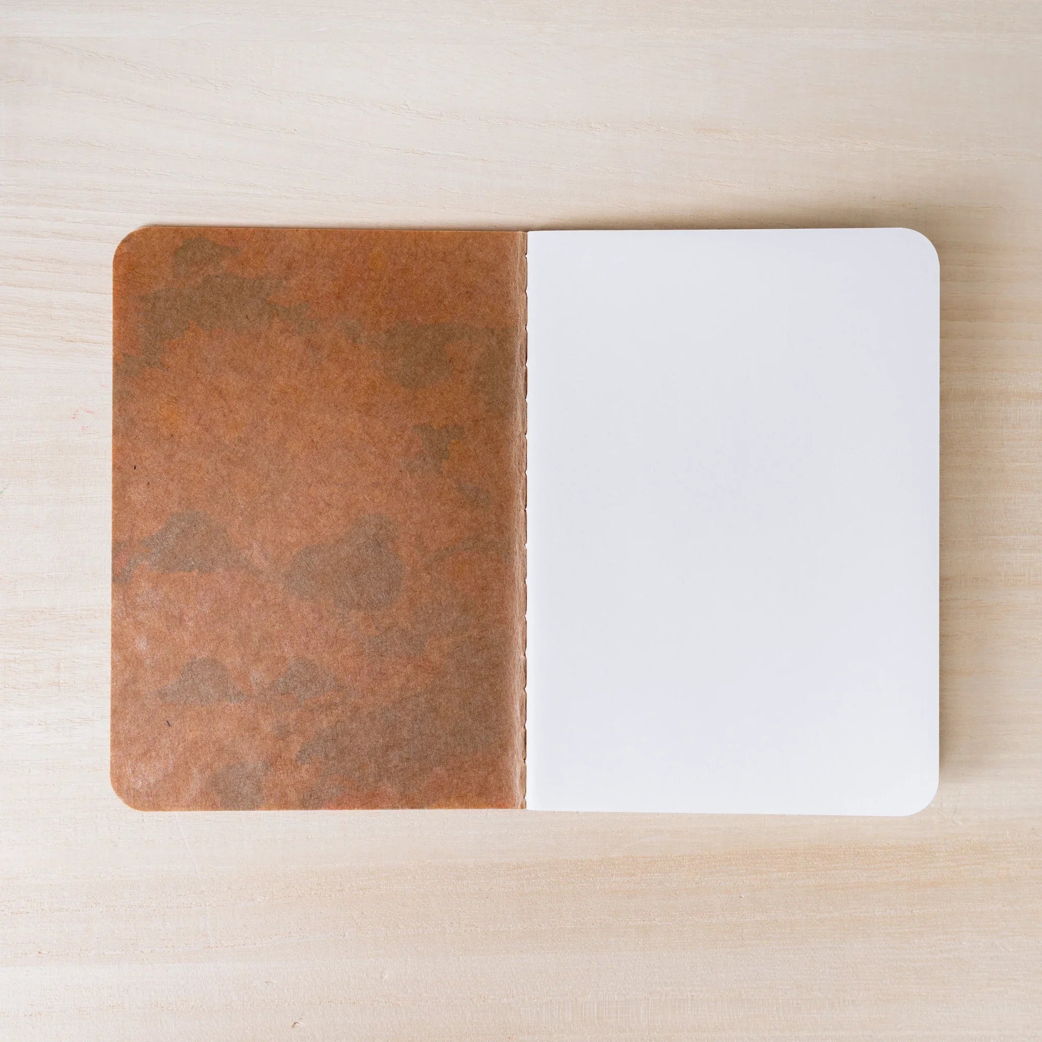RO-BIKI NOTE open flat, brown waxed kraft inner cover on left, blank white page on right, rounded corners visible