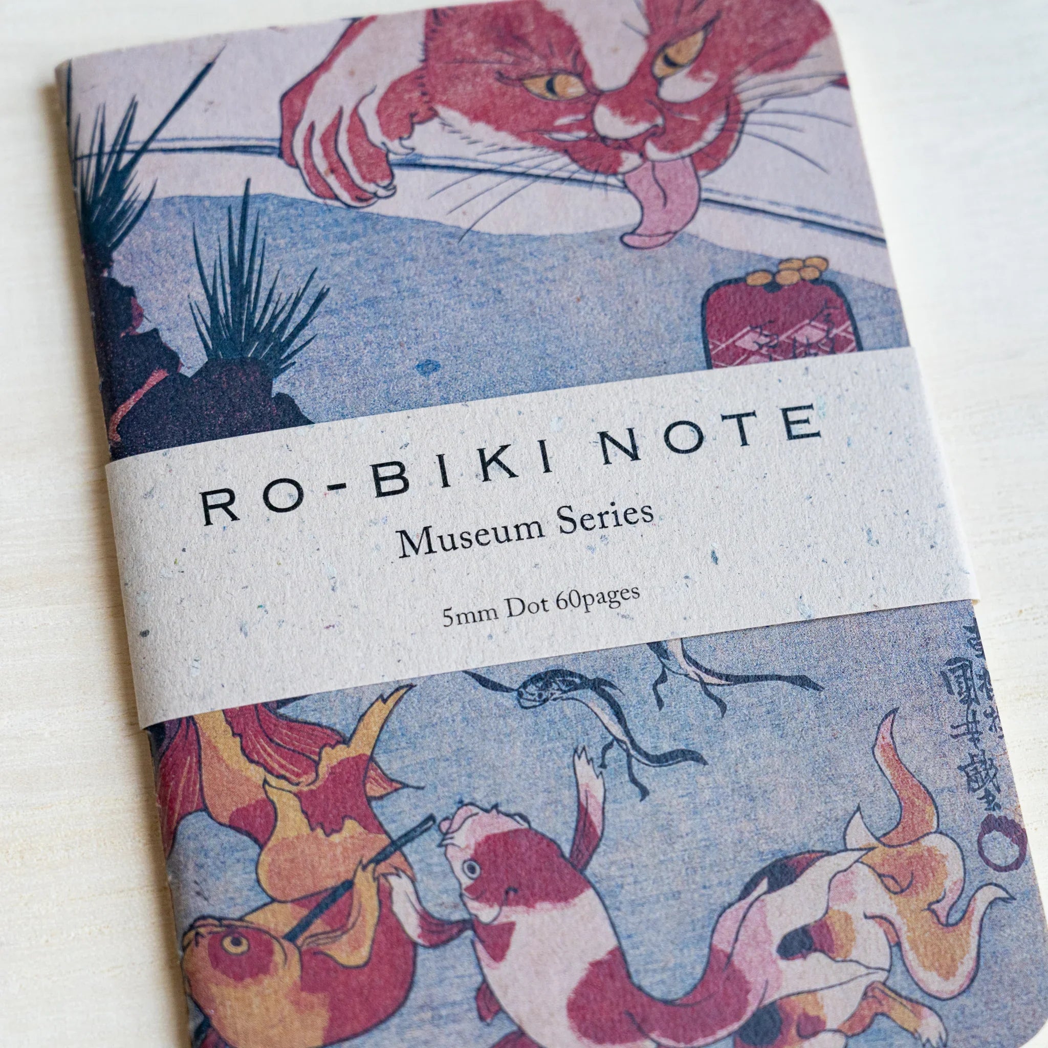 RO-BIKI Kingyo Goldfish notebook angled to show the waxed cover texture and the Museum Series paper band