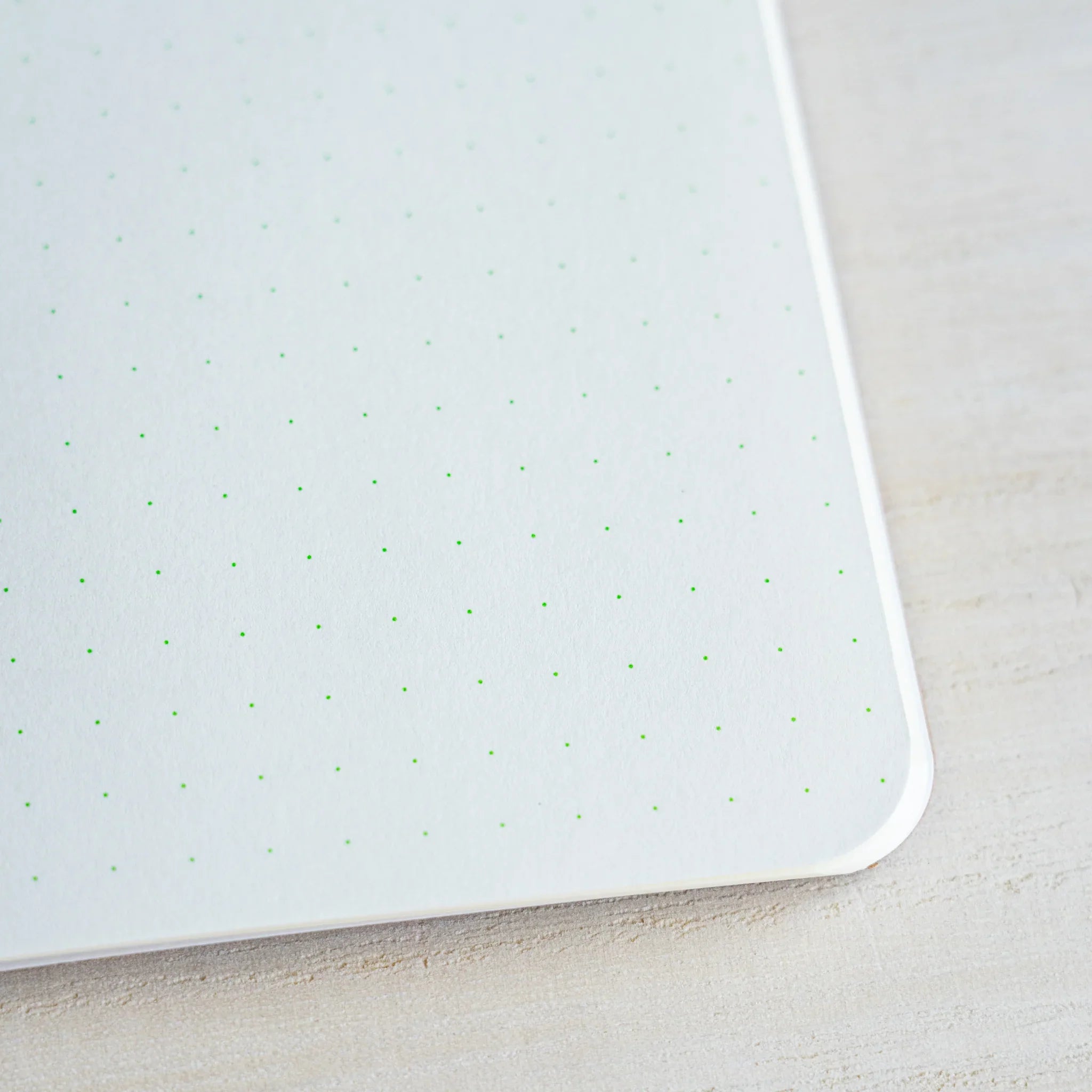 Close-up of pale green 5 mm dot grid printing and the rounded corner of a RO-BIKI notebook page