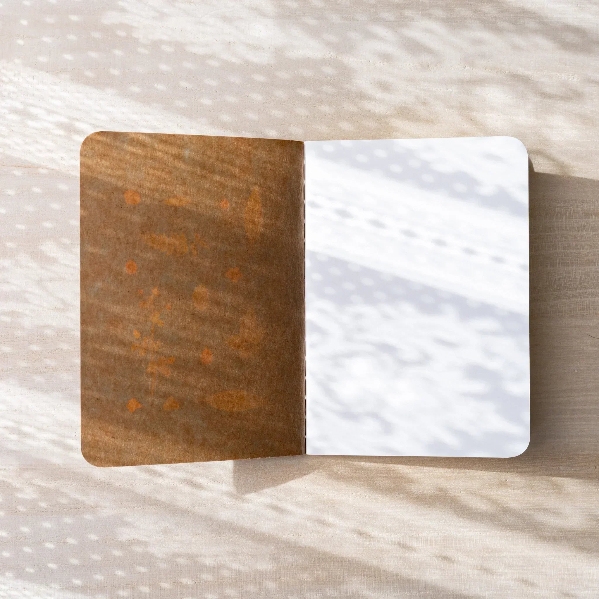 RO-BIKI NOTE Japanese notebook open flat, brown waxed kraft inner cover on left, blank white page on right, rounded corners