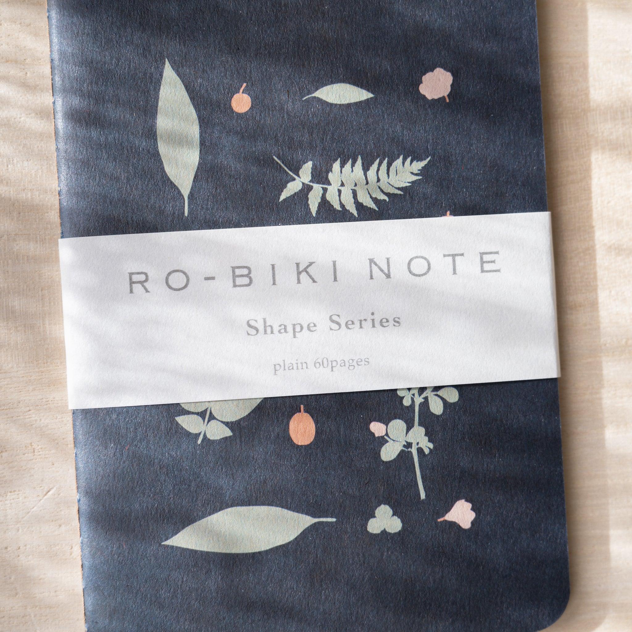 RO-BIKI NOTE Japanese notebook, close-up of navy waxed cover with plant illustrations, belly band with Shape Series text
