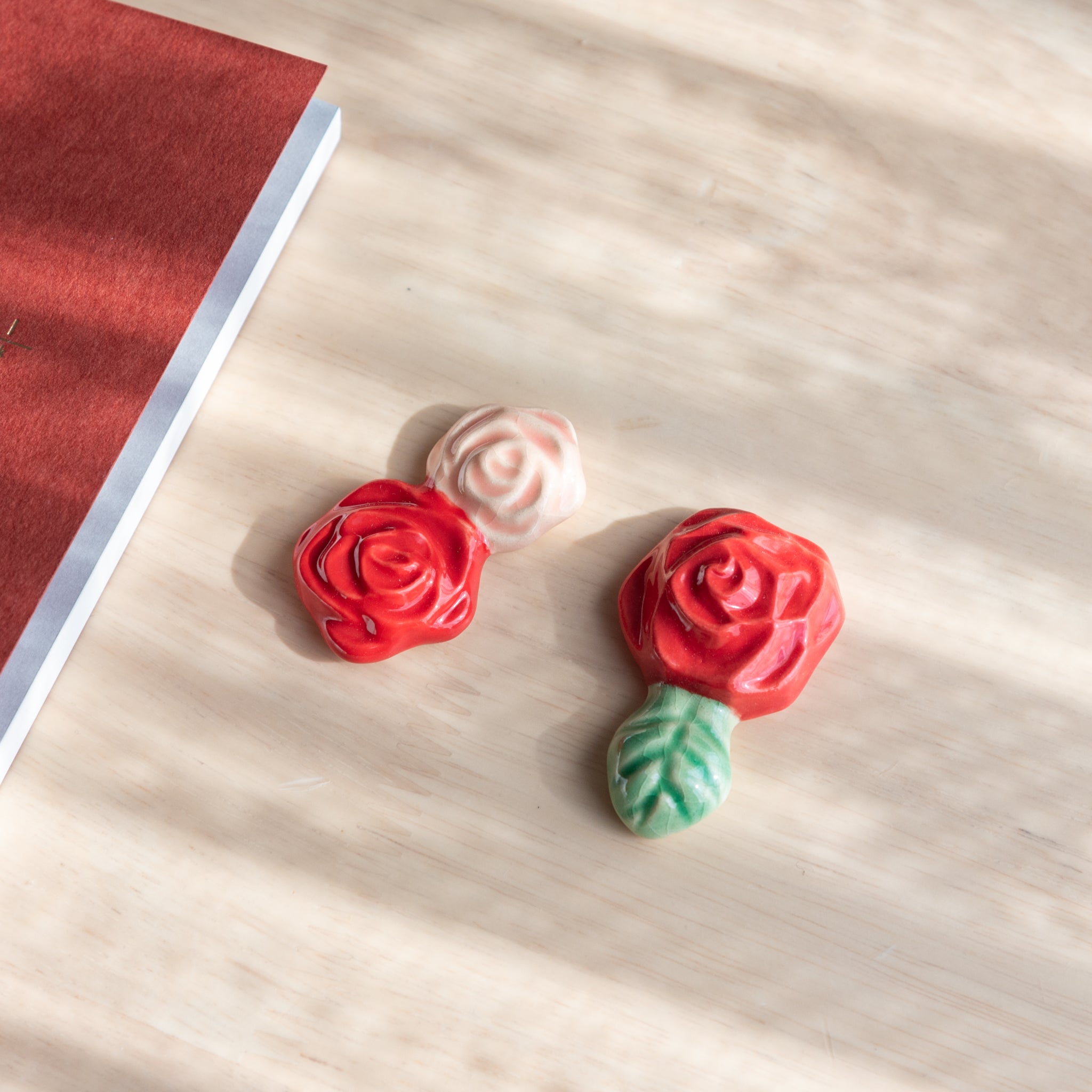 Handcrafted ceramic pen rest shaped like a red rose with a green leaf, perfect for pairing with Japanese stationery items.