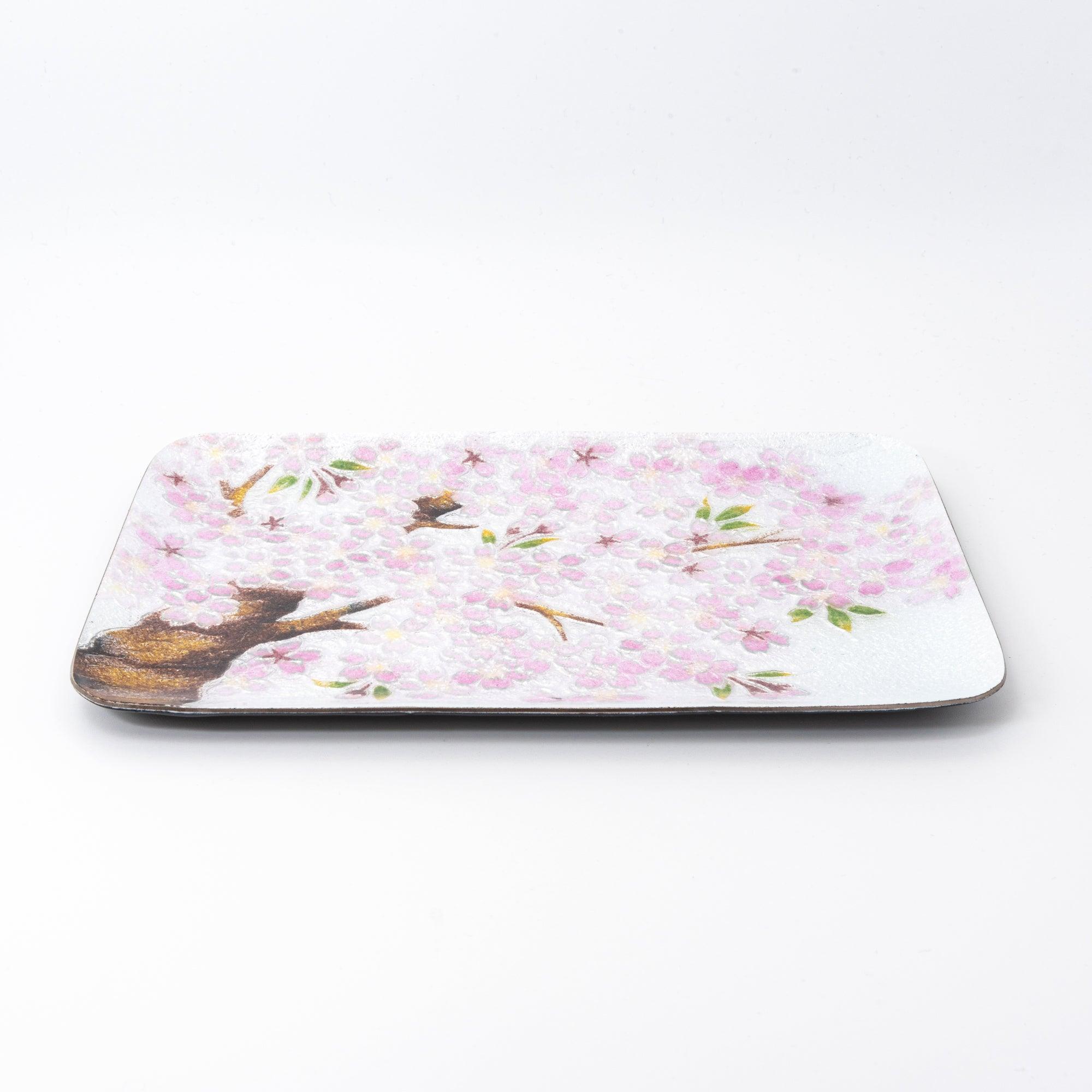 Side angle of a rectangular silver tray adorned with pink cherry blossoms and brown branches, emphasizing its craftsmanship.  