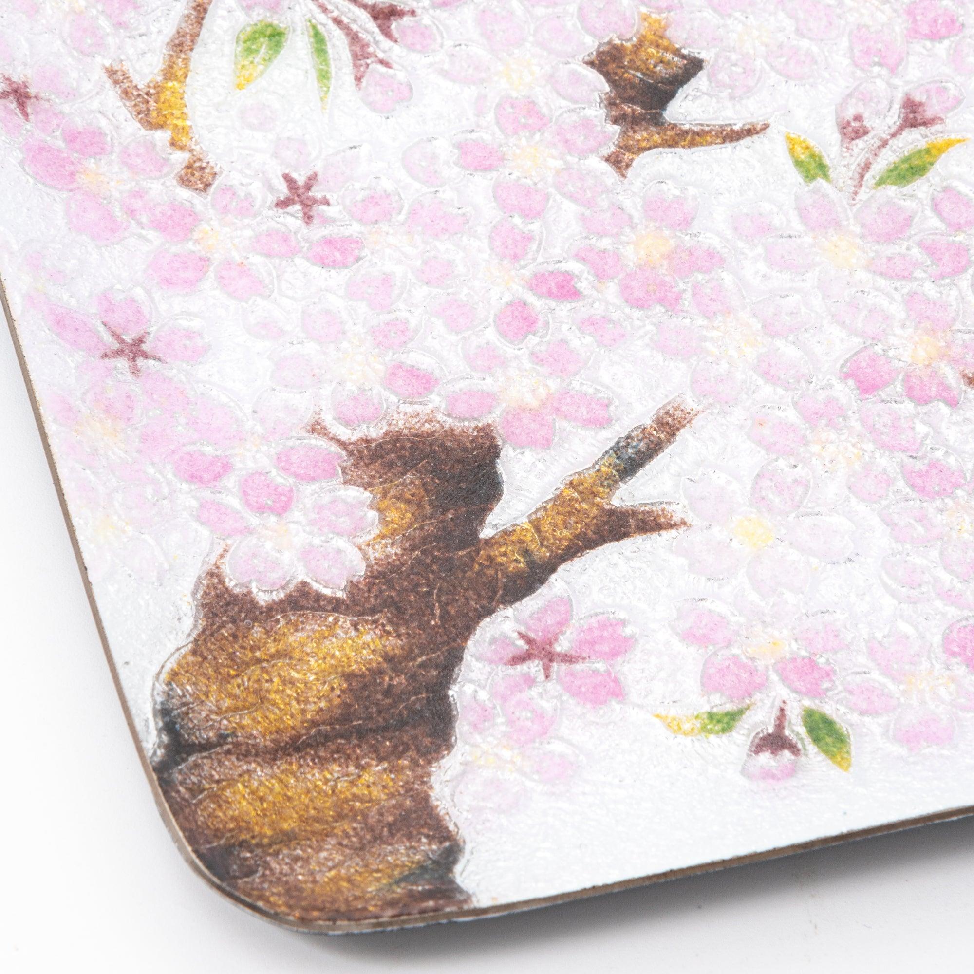 Detailed close-up of a corner of the tray, highlighting the brown branch and textured pink cherry blossom petals.  