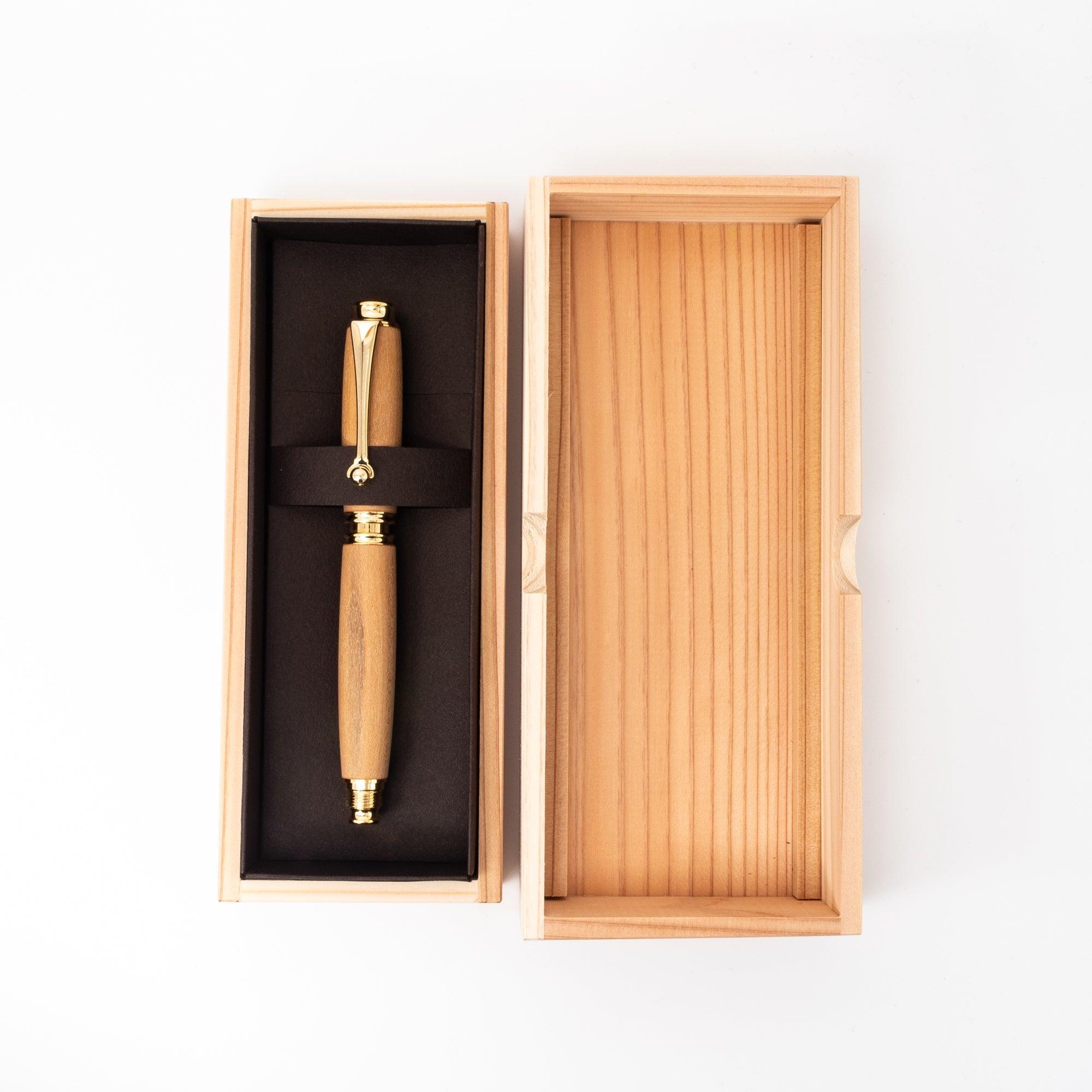 A Japanese fountain pen made of wood with gold details, presented in an open wooden box with black lining, highlighting its luxurious packaging design.