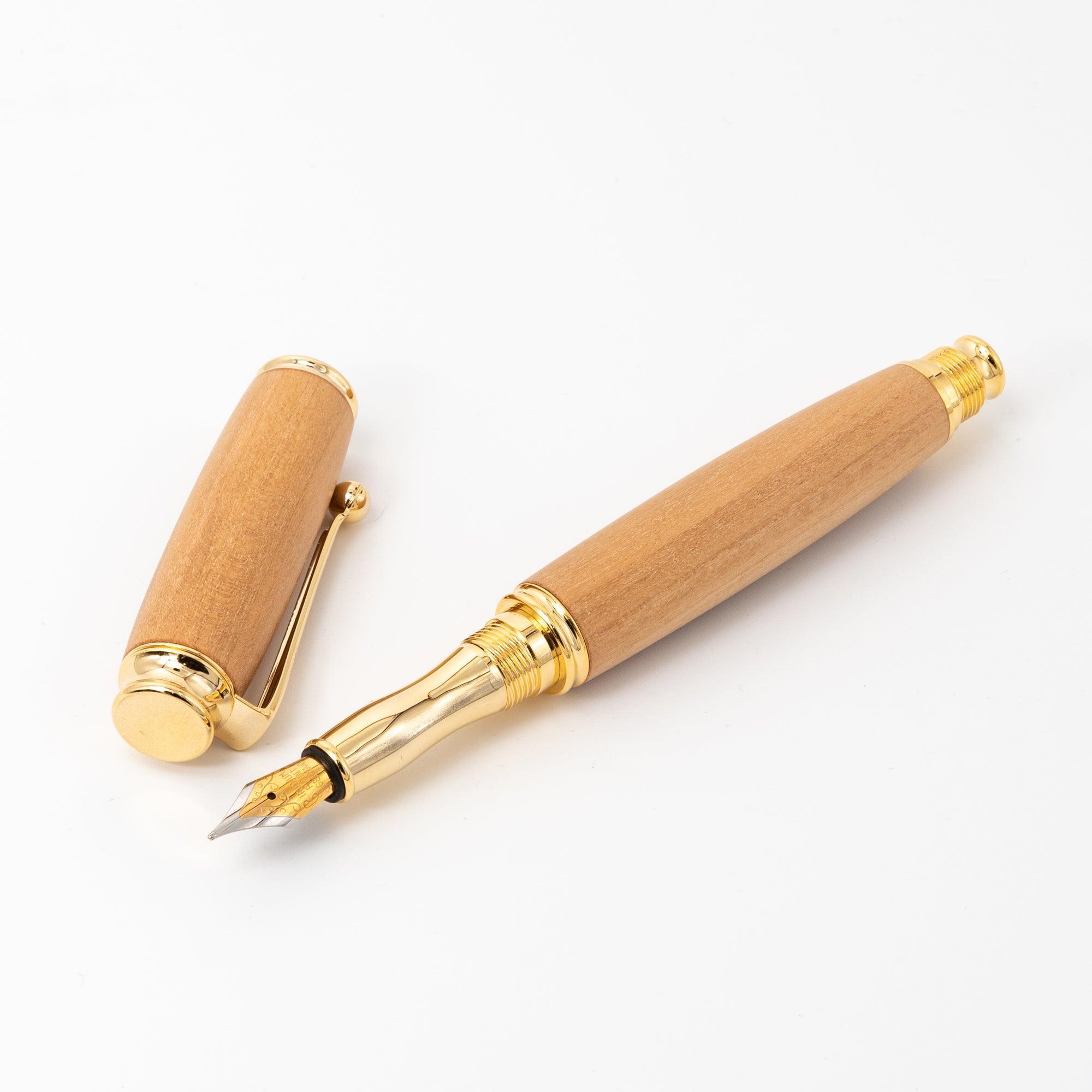 A Japanese fountain pen with a wooden body, gold nib, and removed cap, laid on a white surface to emphasize its sleek and sophisticated design.