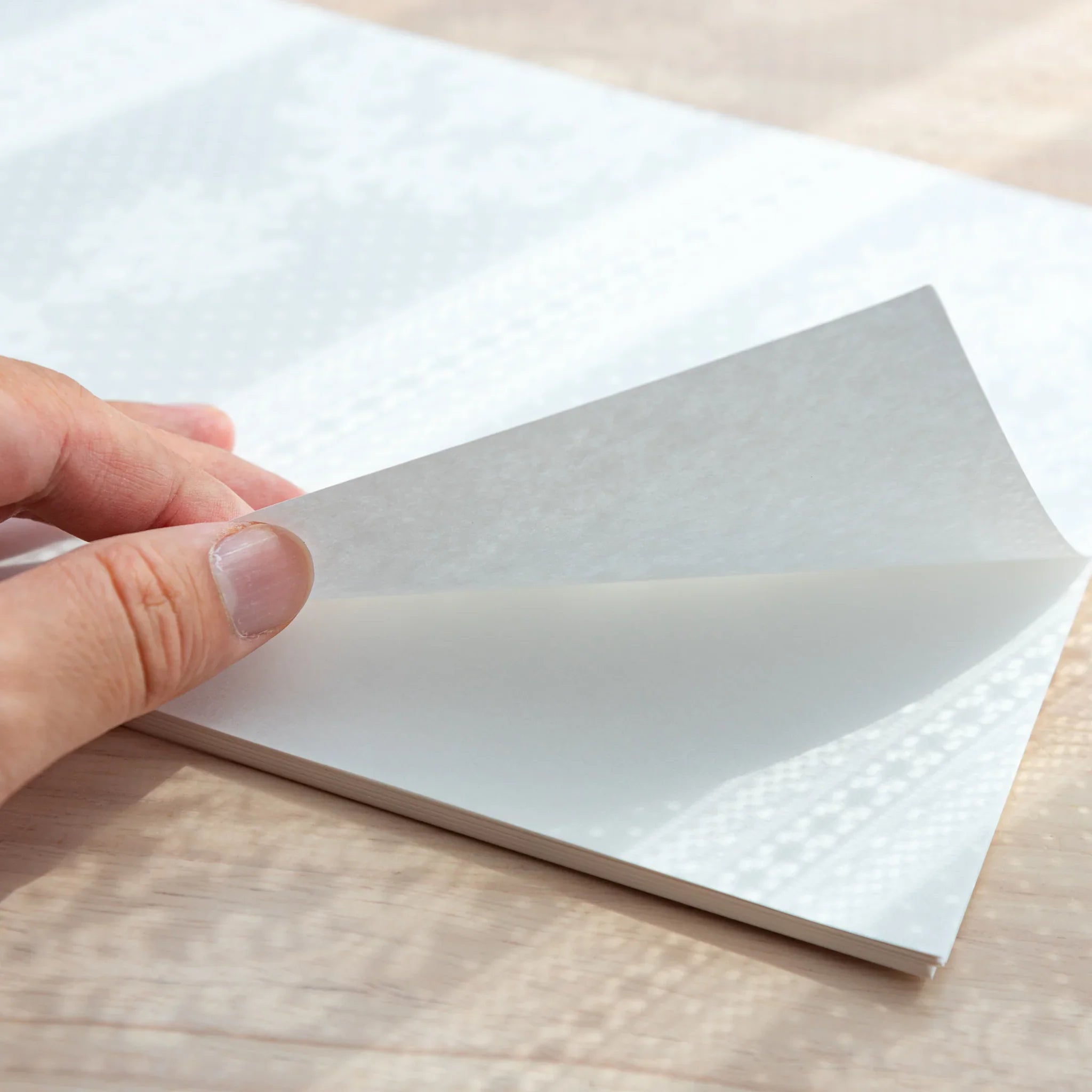 Hand lifting a sheet of A4 Sheep Clouds Bond, showcasing texture and quality of Japanese Loose Leaf Paper for writing.