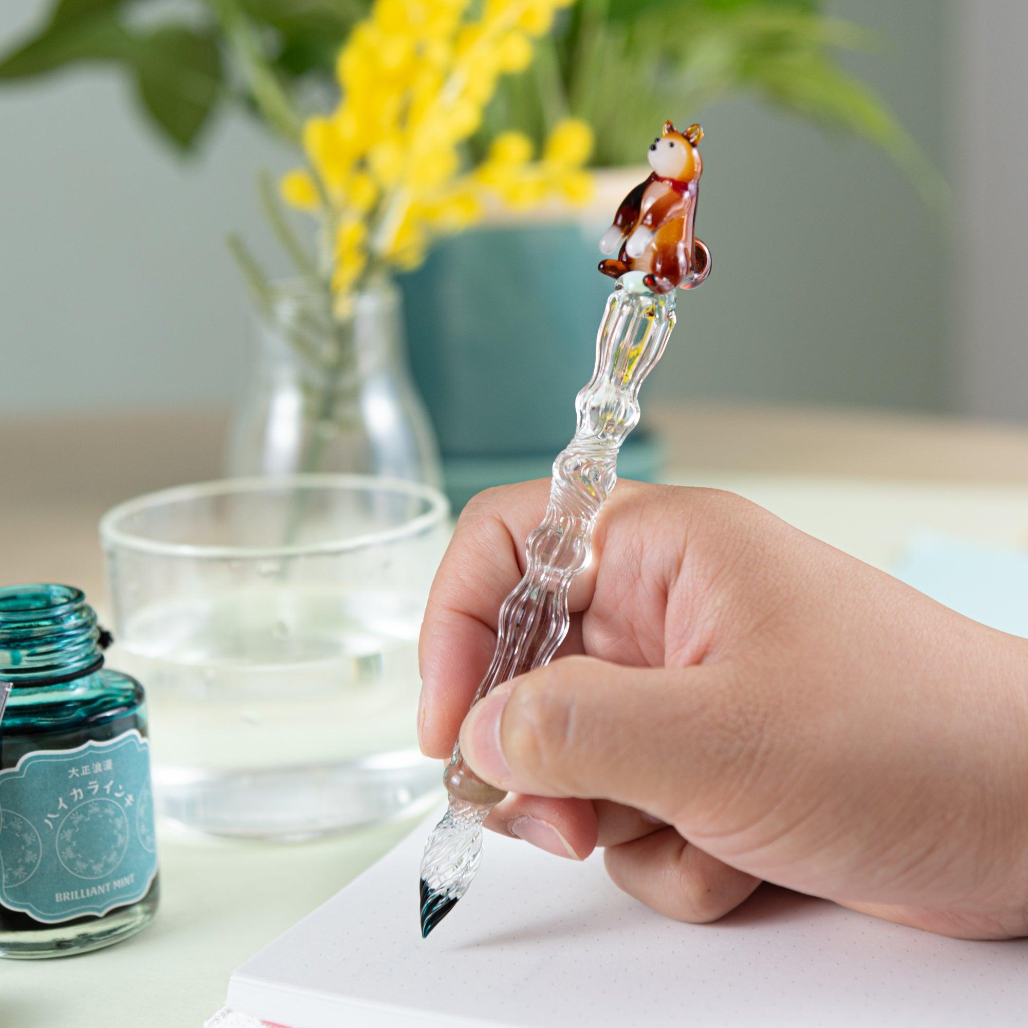 Close-up of Shiba Inu glass pen with clear light green shaft, ready to be dipped in ink. Perfect for collectors.