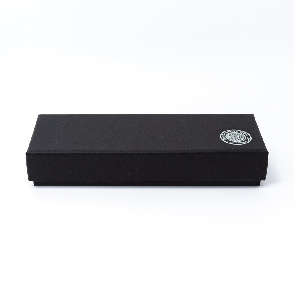 A sleek black pen box with the Synchronicity Glass Art logo embossed on the corner, showcasing the brand's minimalist packaging design.