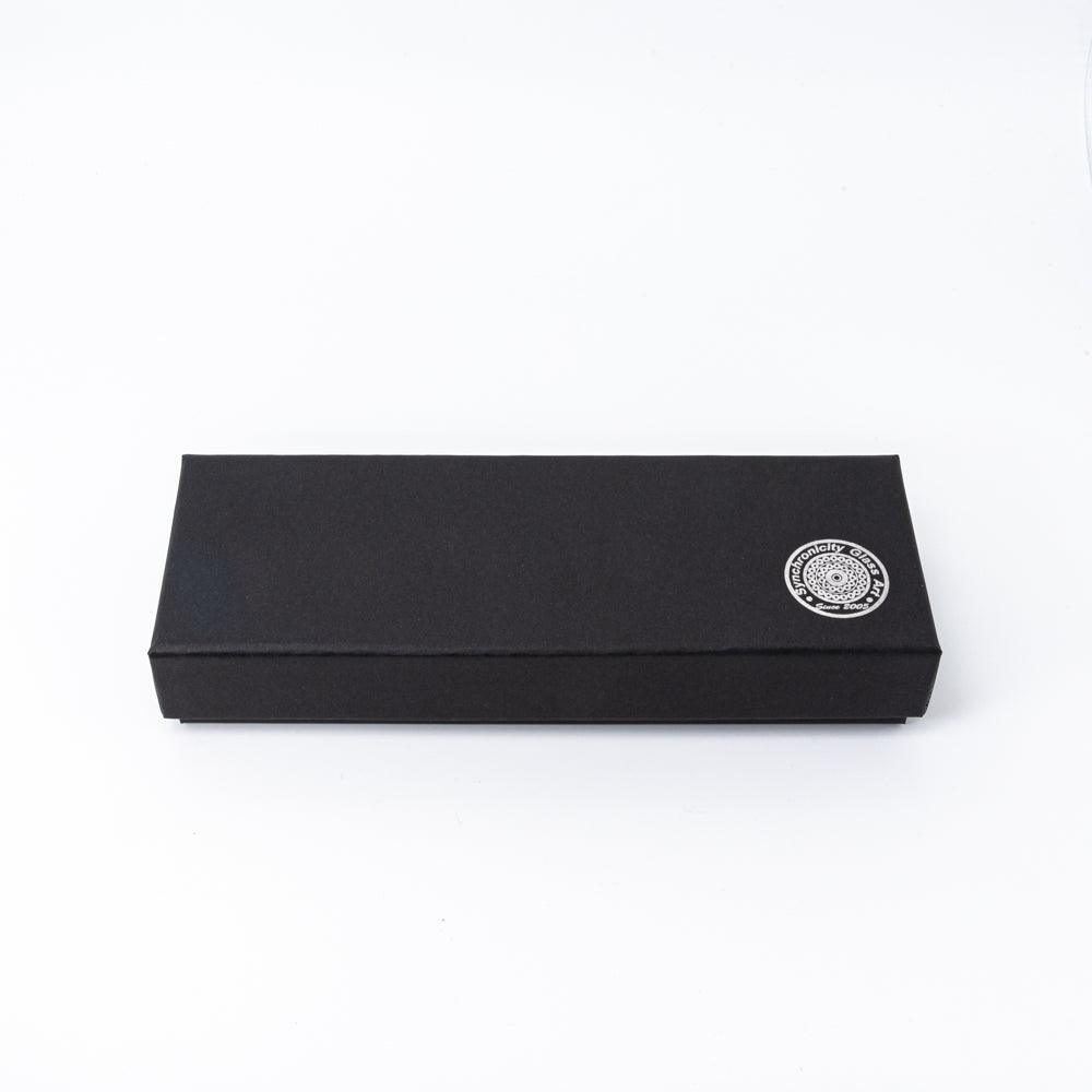 A sleek black pen box with the Synchronicity Glass Art logo embossed on the corner, showcasing the brand's minimalist packaging design.