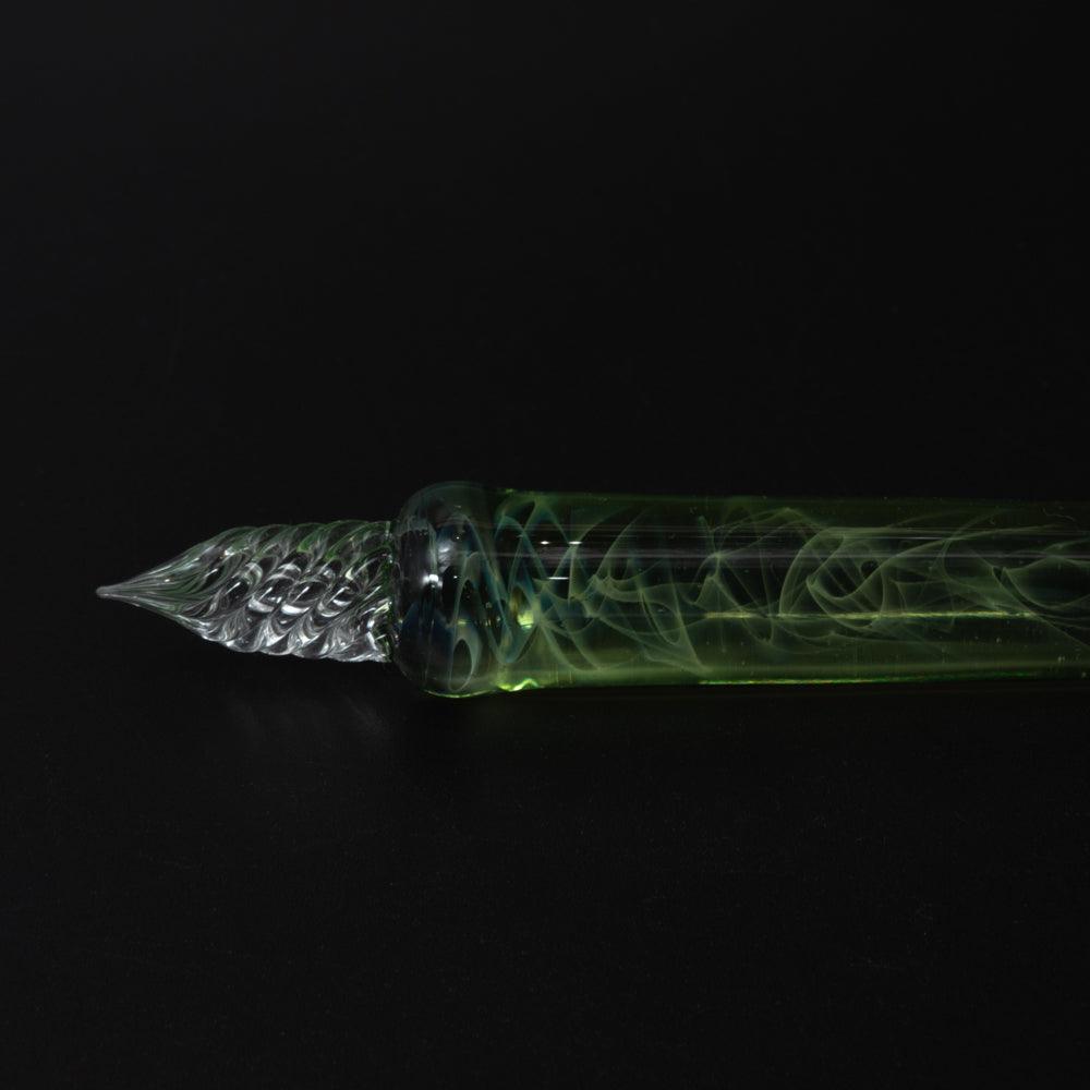 Dark background highlights the green glass pen's intricate design, showcasing the swirling patterns inside the translucent body.