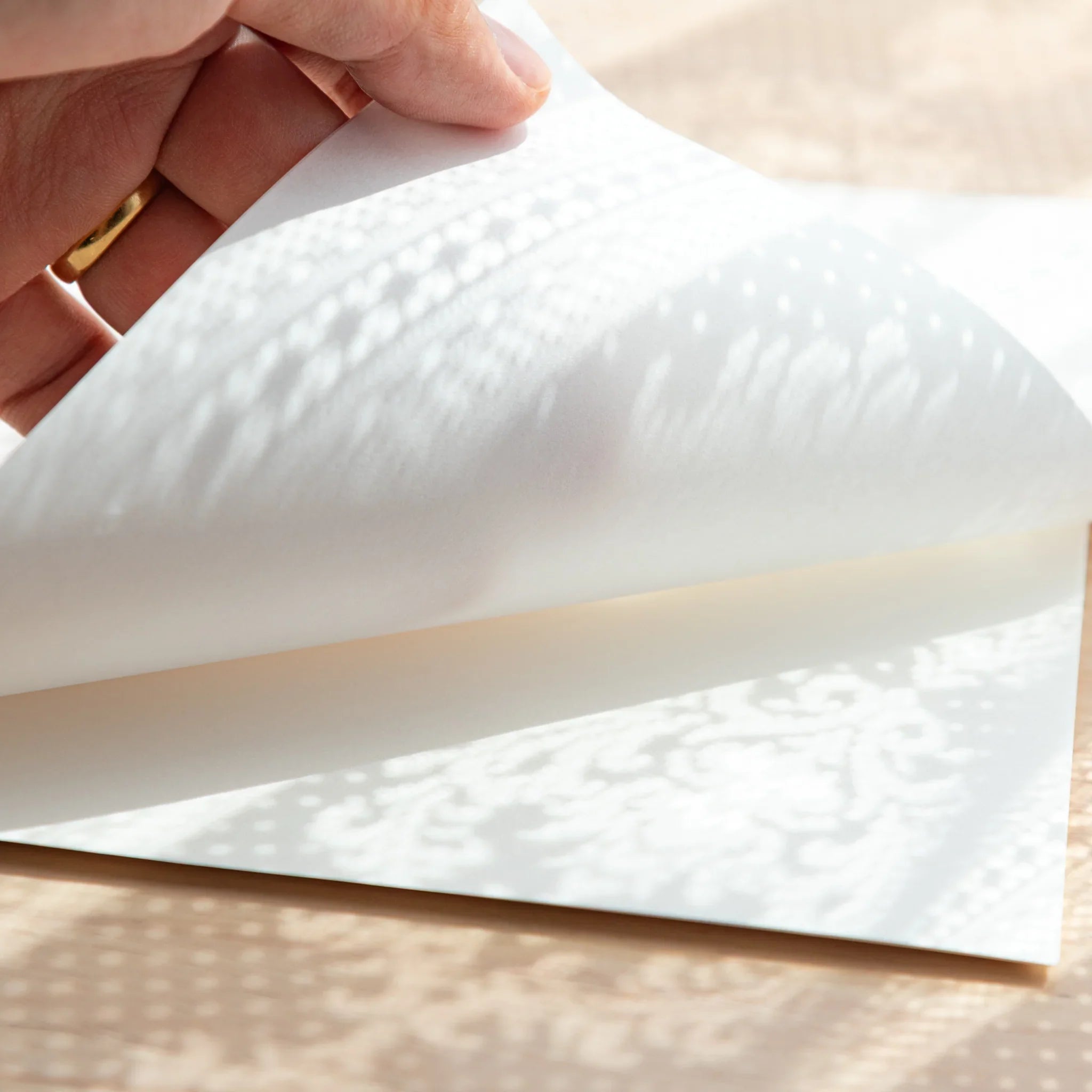 Slightly bent Smooth Onion Skin sheet with lace patterns faintly visible through its translucency.