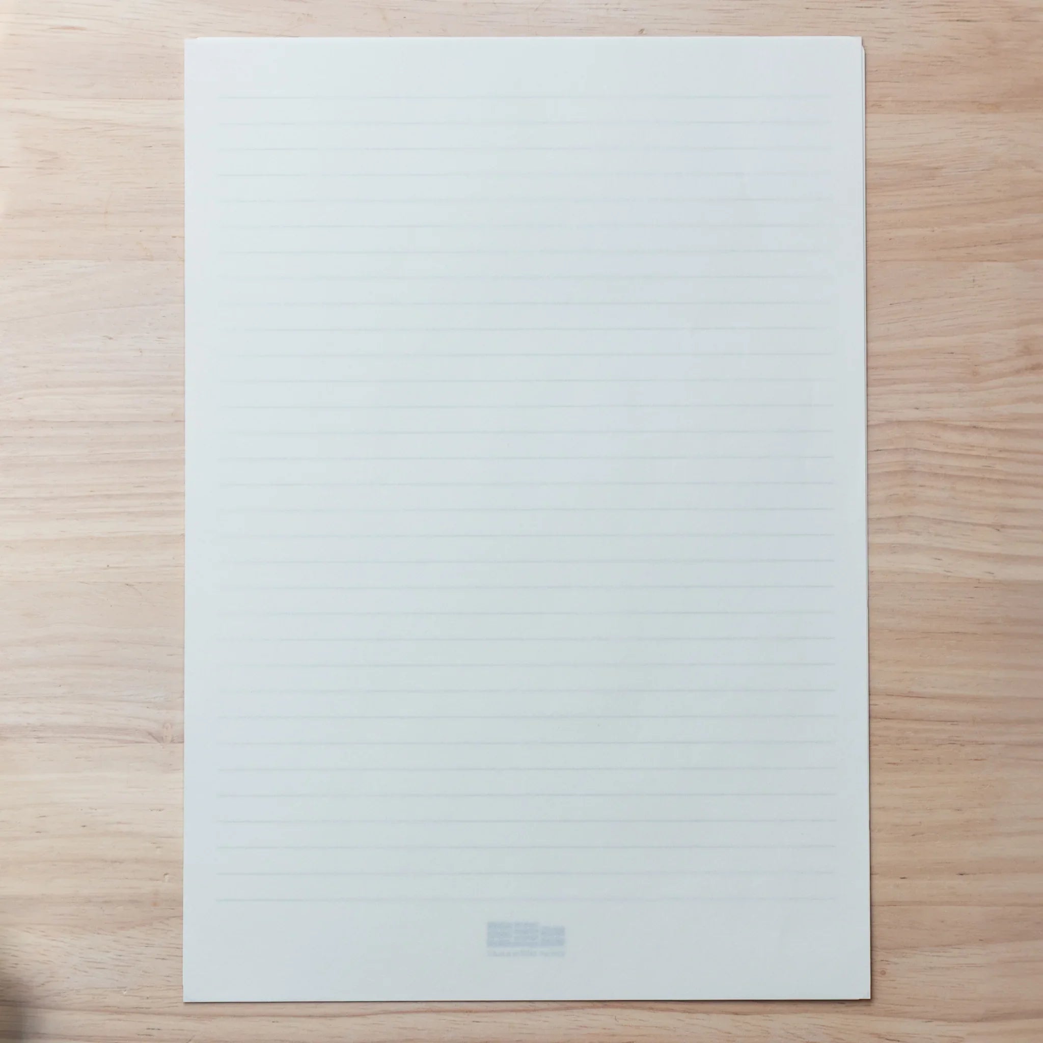 Blue ruled underlay sheet placed beneath Onion Skin loose leaf paper, used for guiding neat handwriting.