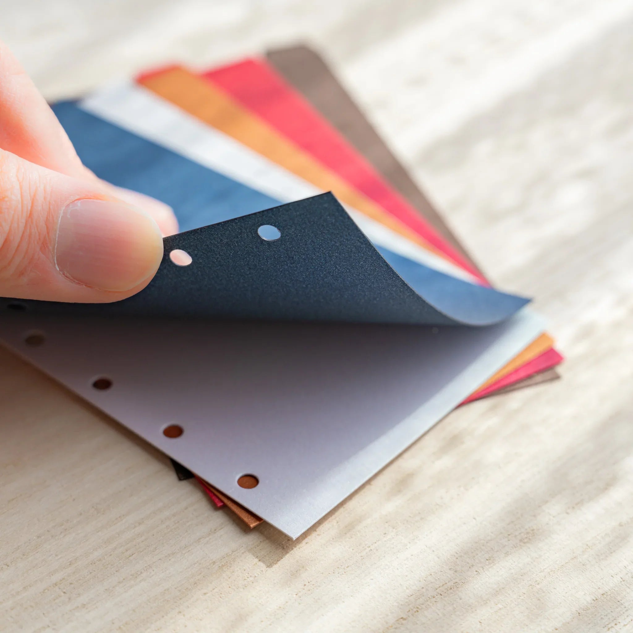 Japanese Stationery Stardream top-tab index dividers for Mini 6 planners fanned out, hand flipping through colorful sheets.